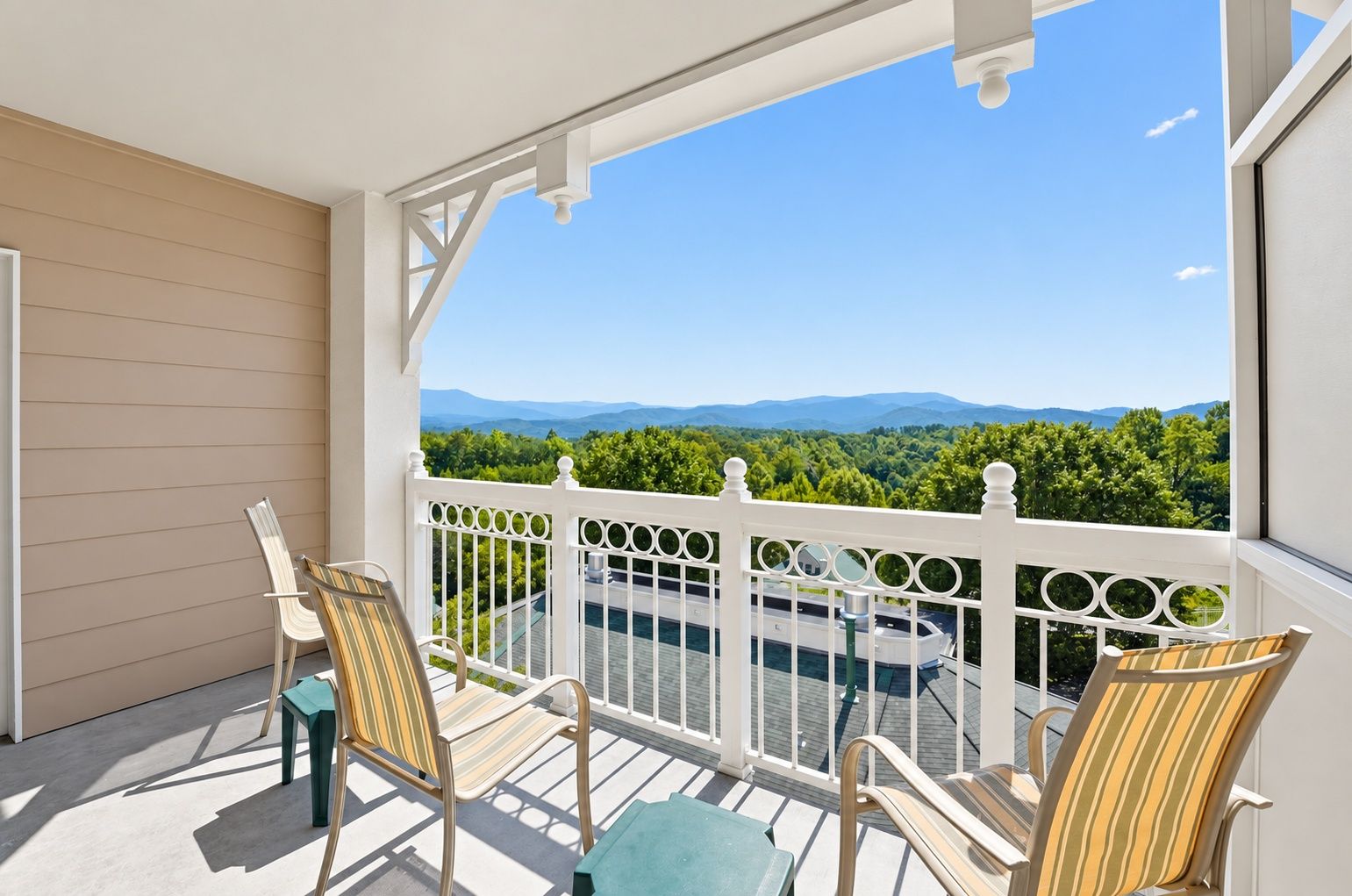 image Balcony with lounge chairs and a view of green hills and distant mountains.