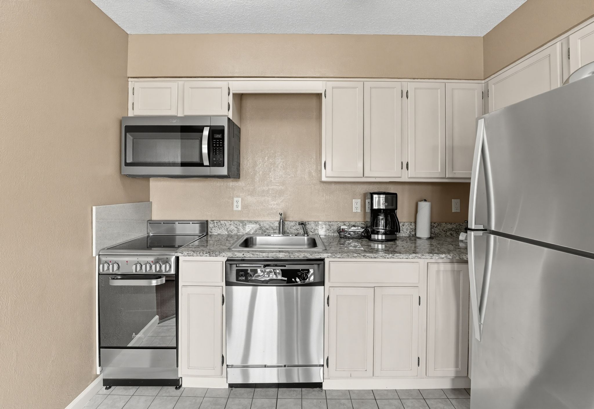 image Kitchen with a stainless steel refrigerator, dishwasher, range, and microwave.