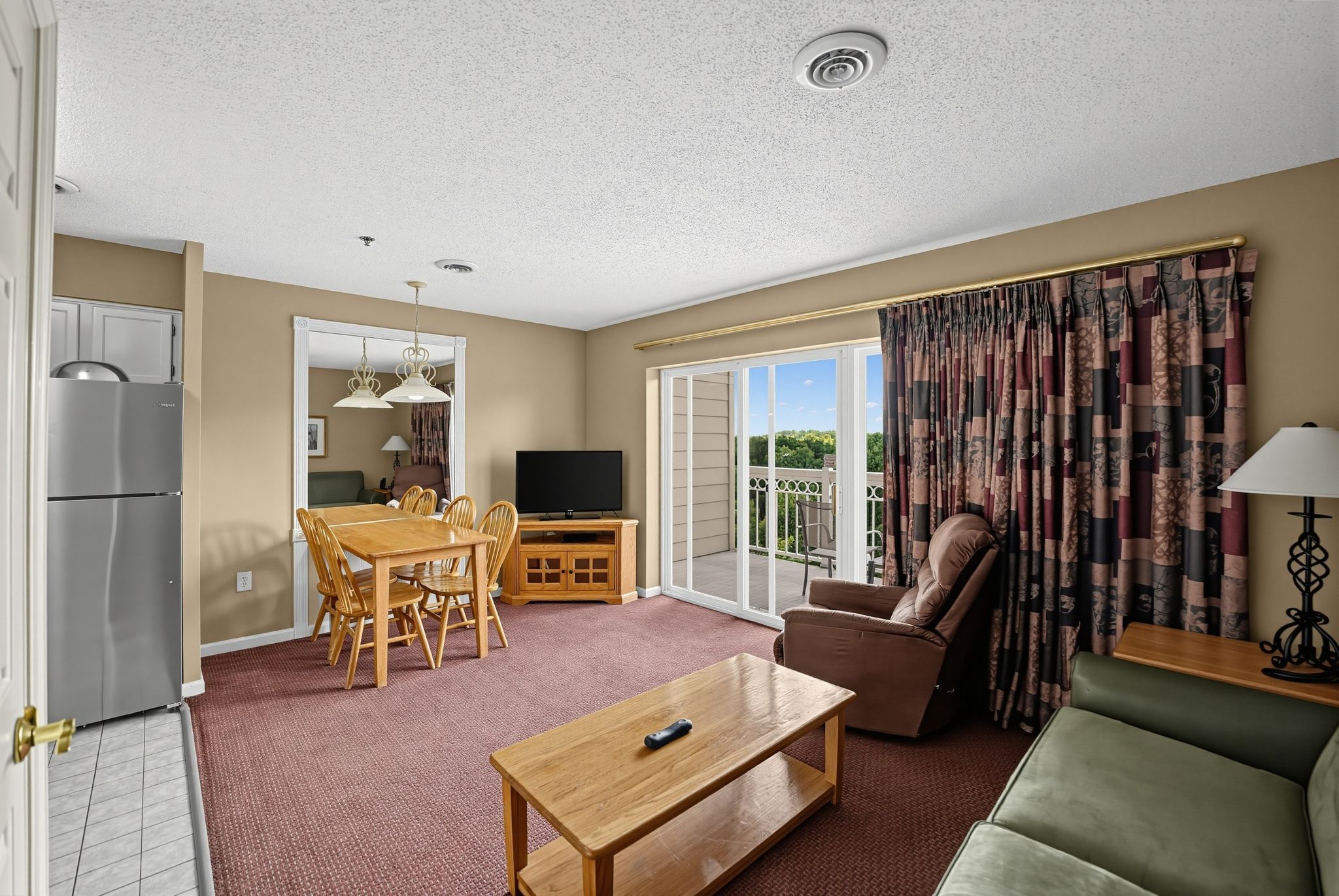 image Living and dining area with a TV, table and chairs, and sliding doors to a balcony.