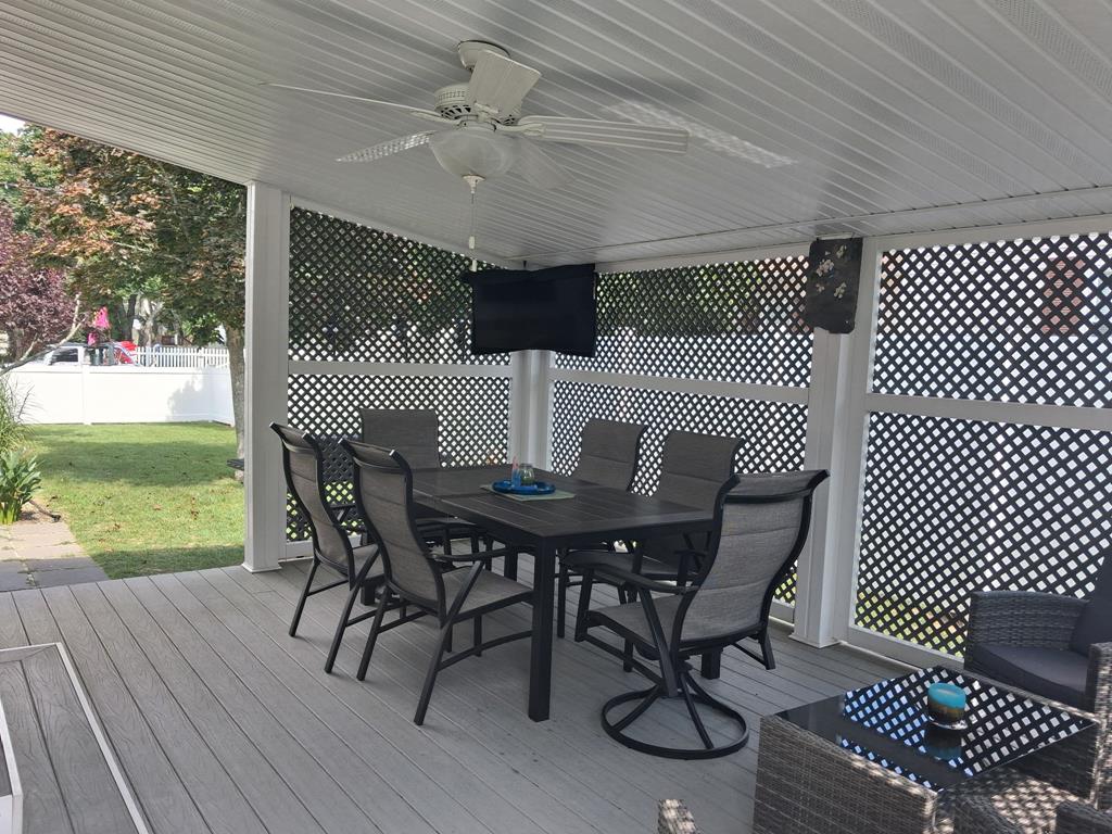 image Covered deck with dining table and chairs, ceiling fan and wall-mounted TV