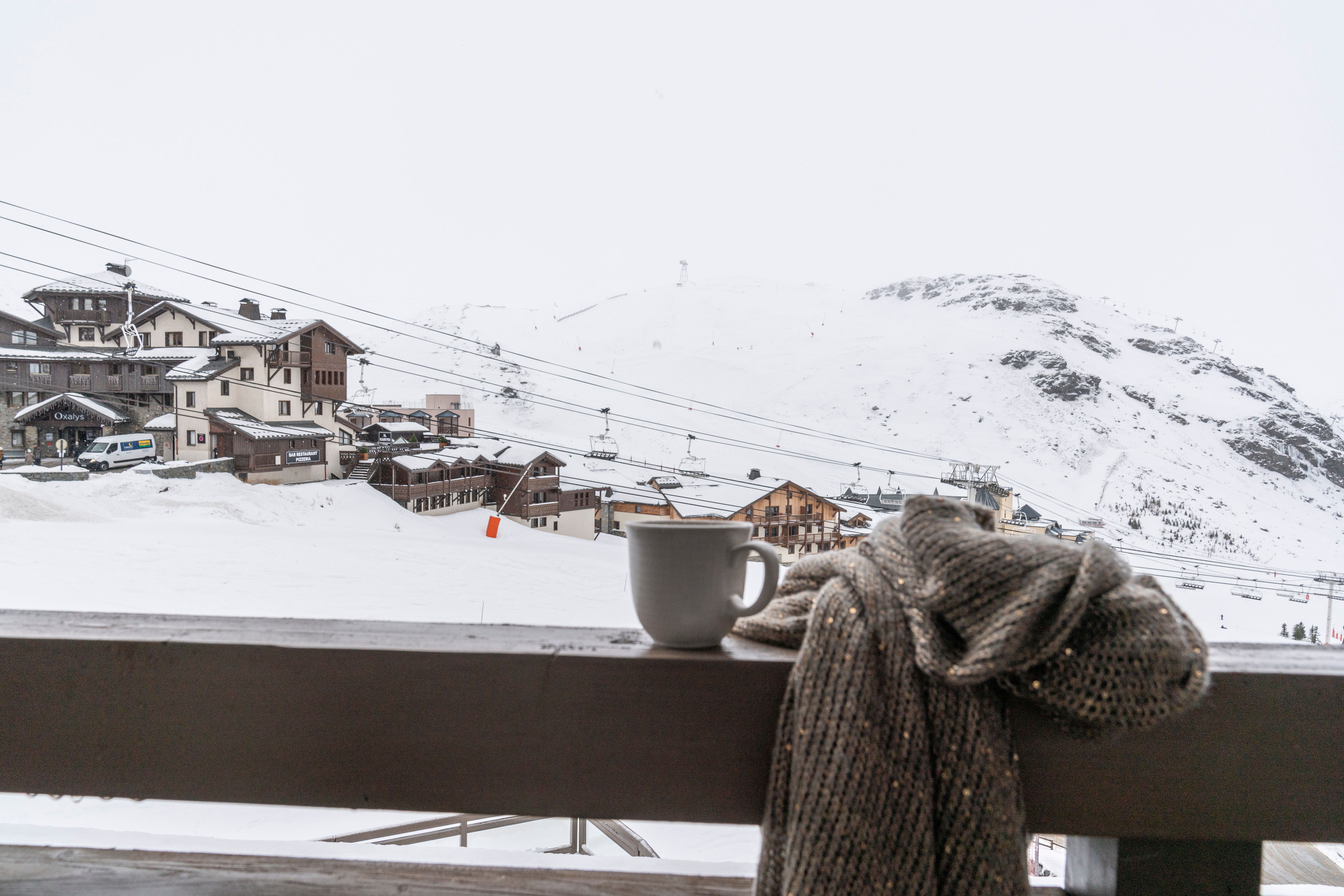 image A coffee on the balcony with the ski lift, snowy rooftops and mountain range in front of you.