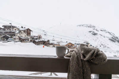 A coffee on the balcony with the ski lift, snowy rooftops and mountain range in front of you.