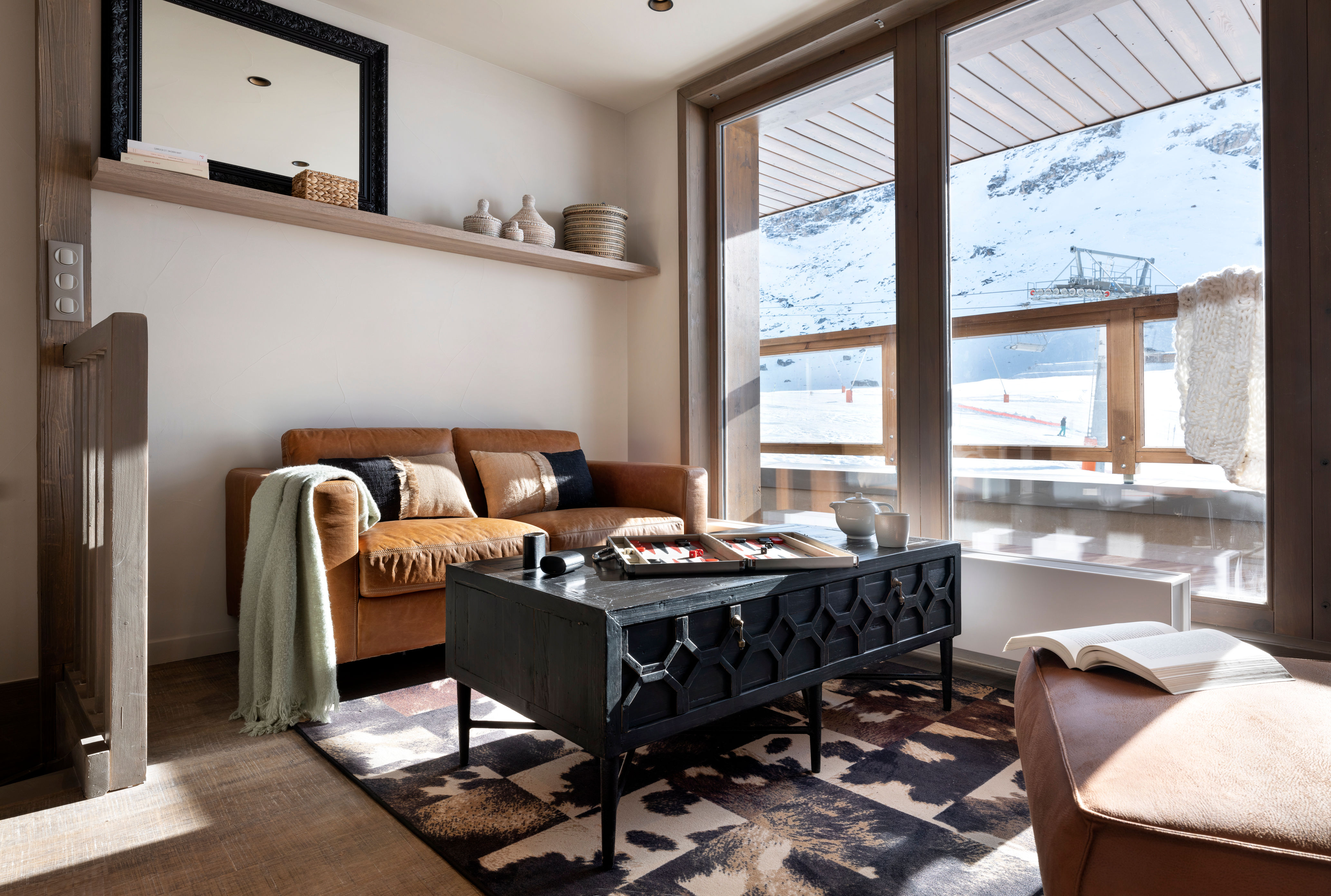 image Wide windows frame the snowy view beside the sofa, with a shelf of decor above.