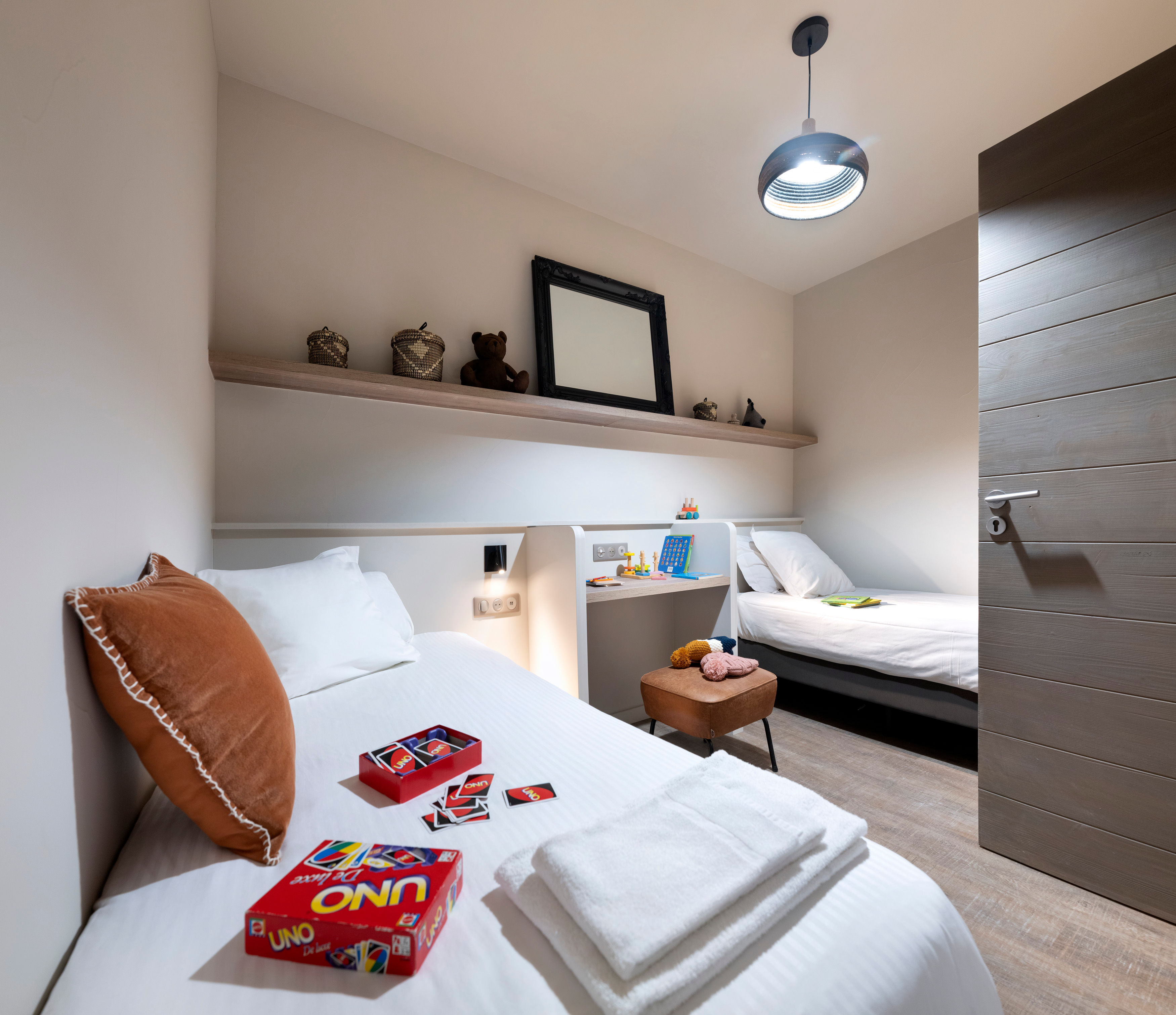 image Twin beds with white bedding sit under a low shelf, with a small seating corner beside them.
