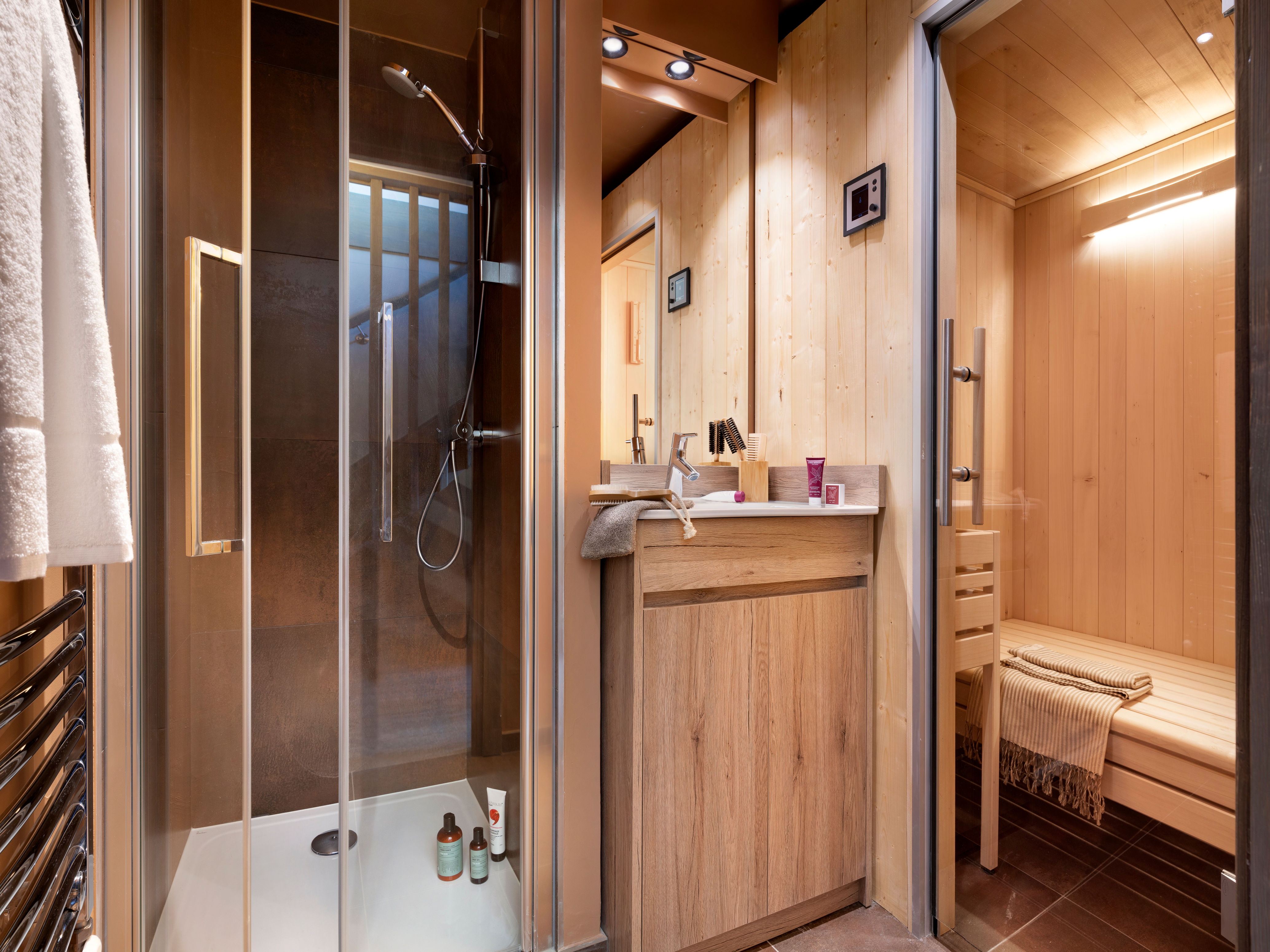 image Light wood walls, dark tiles and a glass shower sit beside the private sauna.
