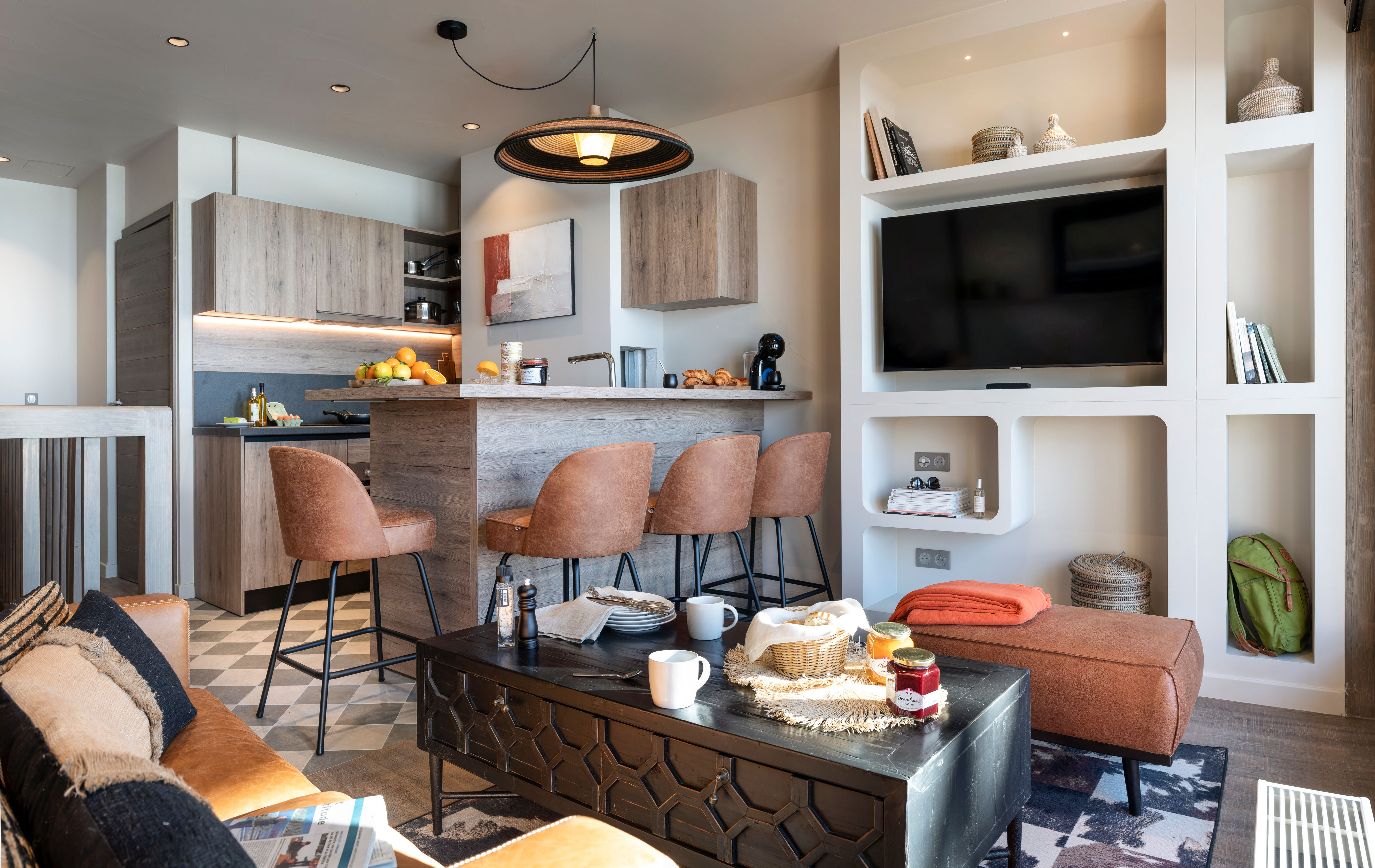 image Geometric floor tiles and wooden cabinets link the kitchen to the dining and seating area.