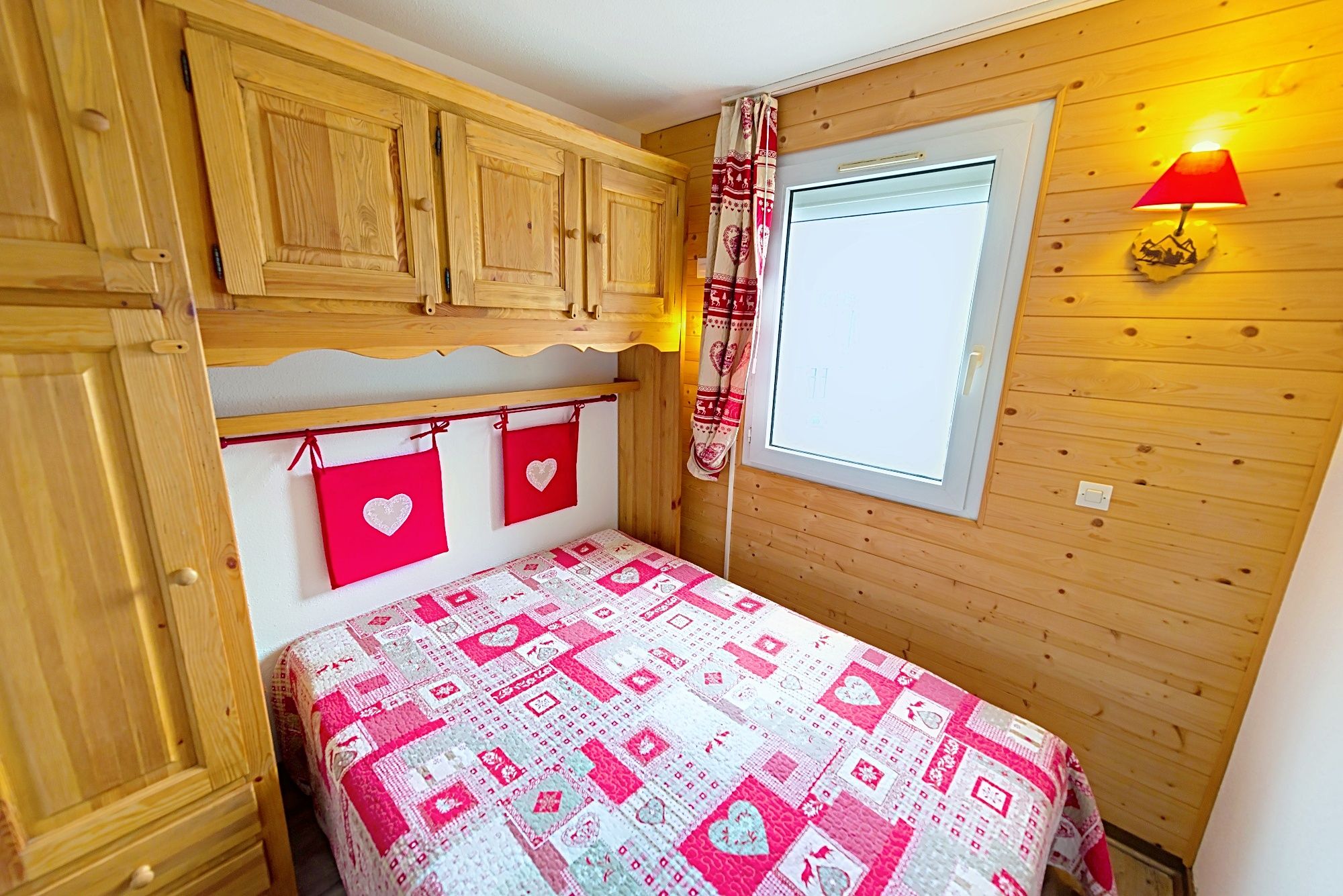 image Wood-panelled bedroom with a double bed and heart-themed decor, calm after a day out.
