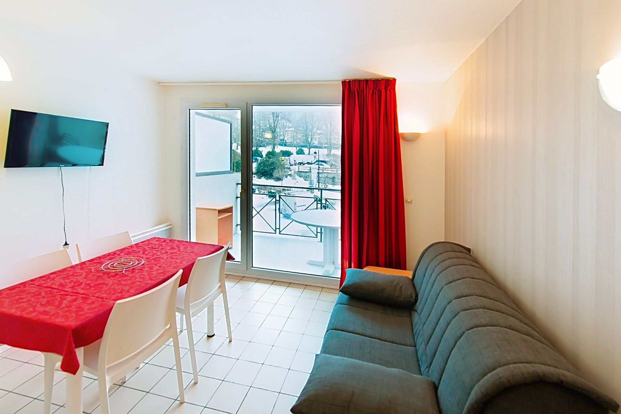 image Red dining table by a large glass door opening outdoors.