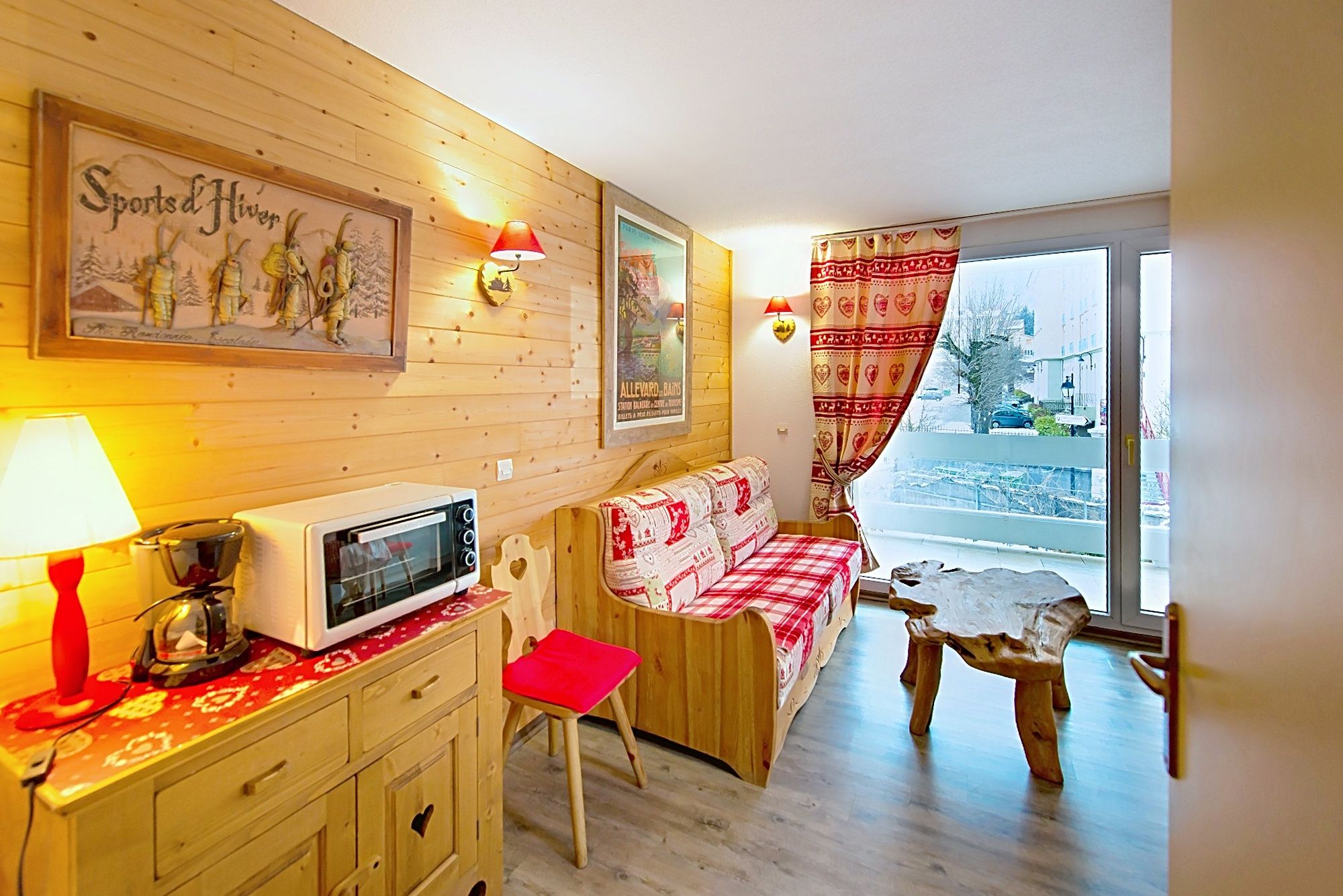image Wooden furniture and a patterned couch in a living area lit by a large window.