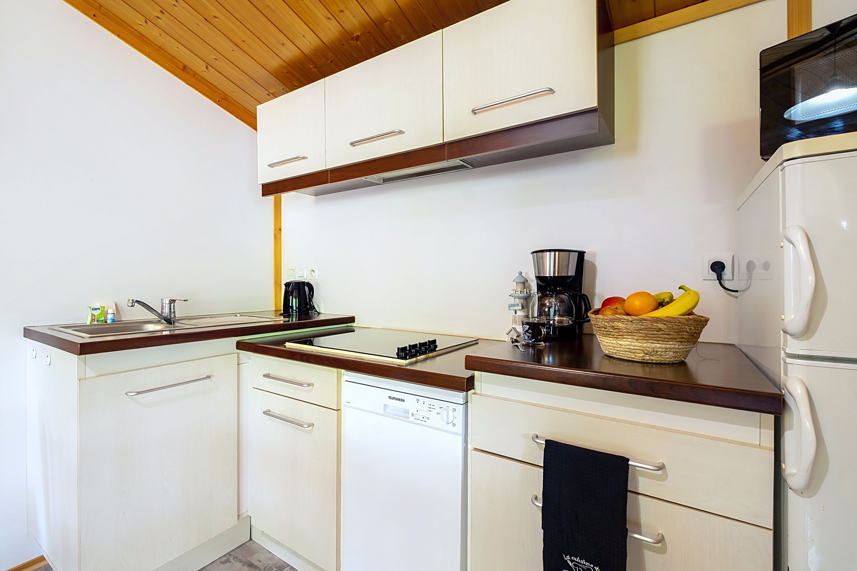 image White cabinets and light wood worktops frame the kitchen, with a bowl of fruit set out on the counter.