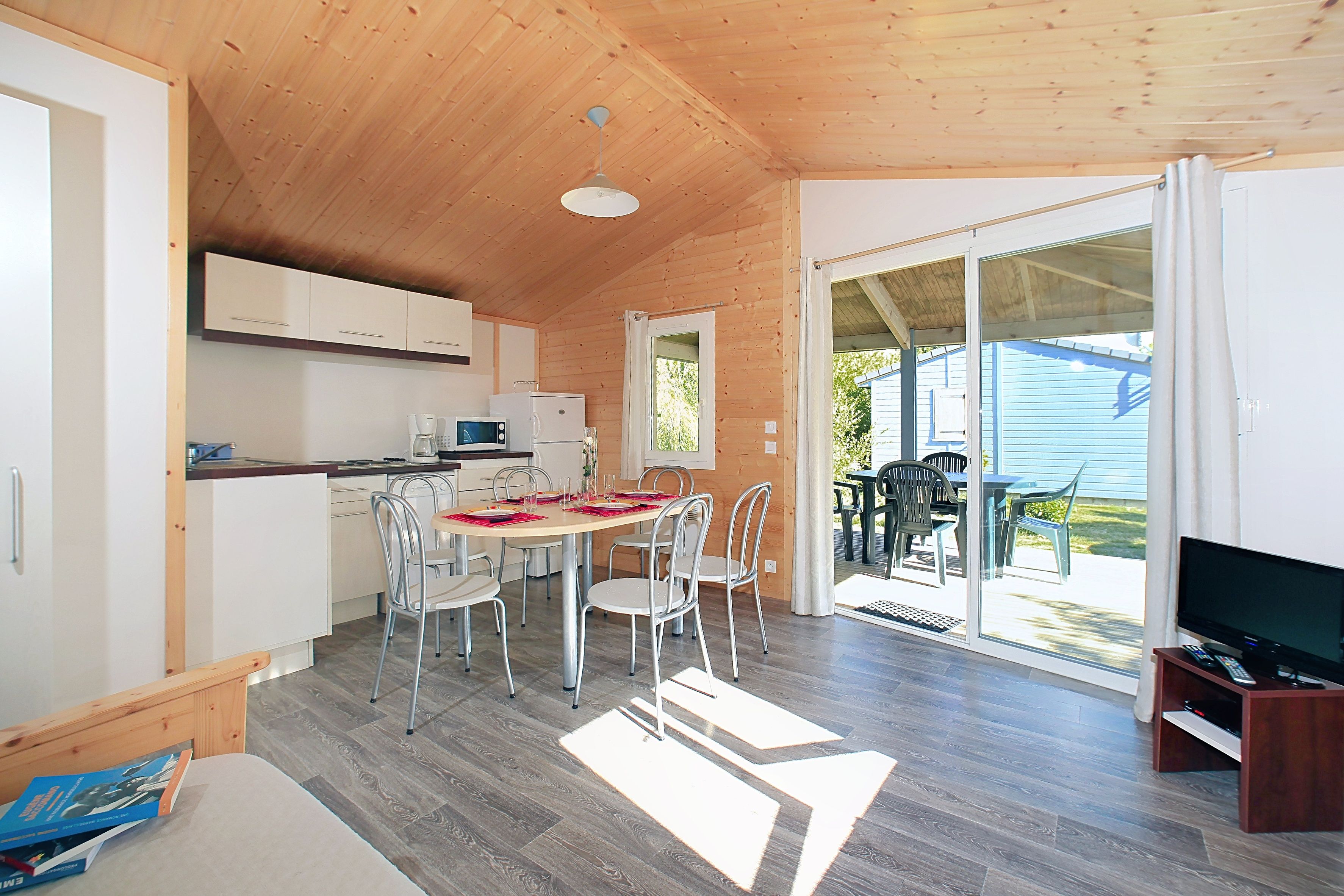 image A vaulted wooden ceiling rises over the living area, with outdoor furniture visible on the deck beyond the glass doors.