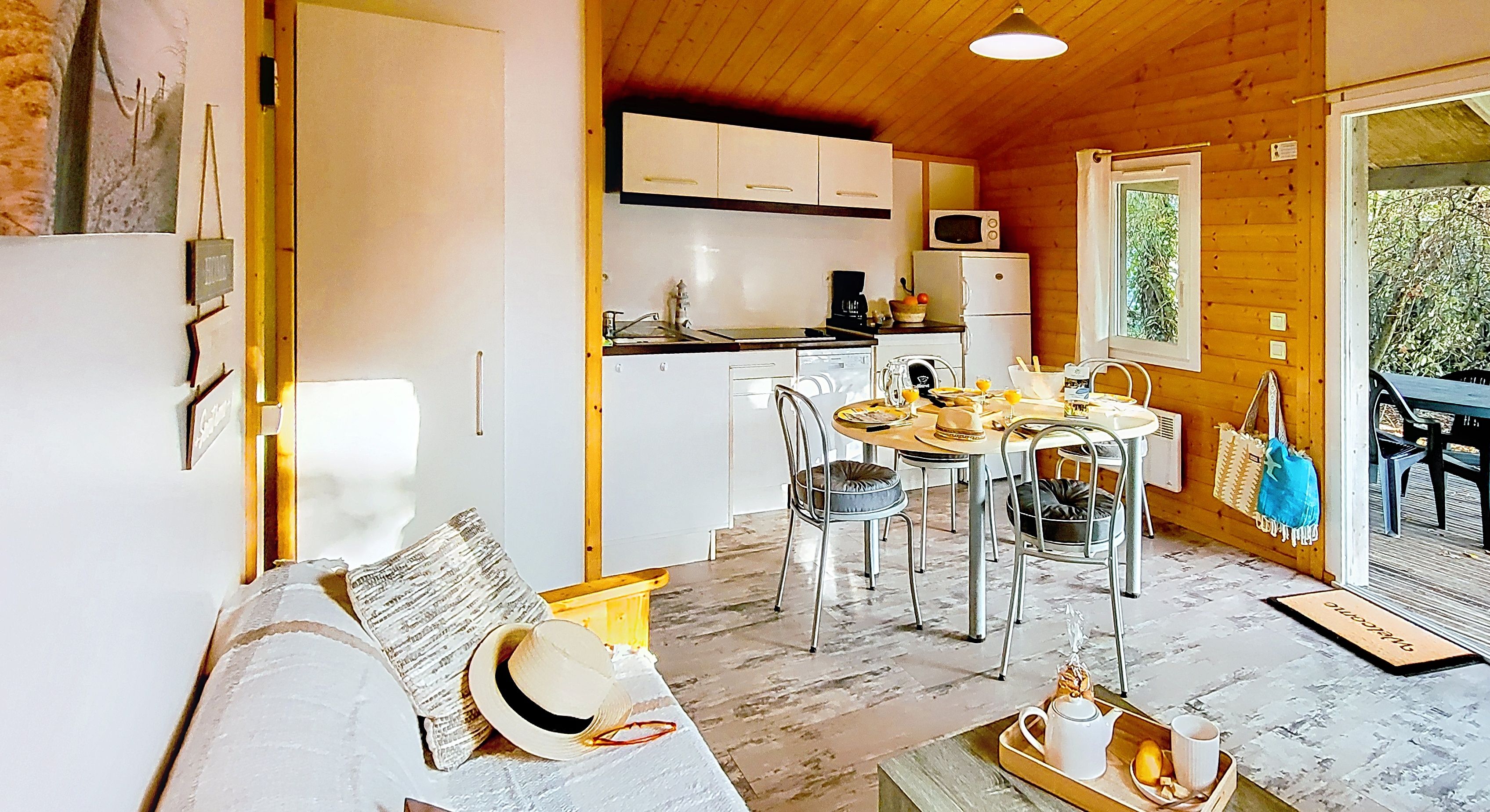 image A round table laid for a meal sits beside a small sofa, with a sun hat resting on the cushions.