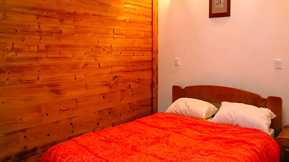 image Rest easy beneath a warm orange quilt, with timber-clad walls adding a touch of mountain cosiness.
