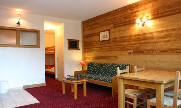 image Warm wood panelling and a floral-patterned sofa give the living space a snug alpine charm, ideal for slow evenings together.