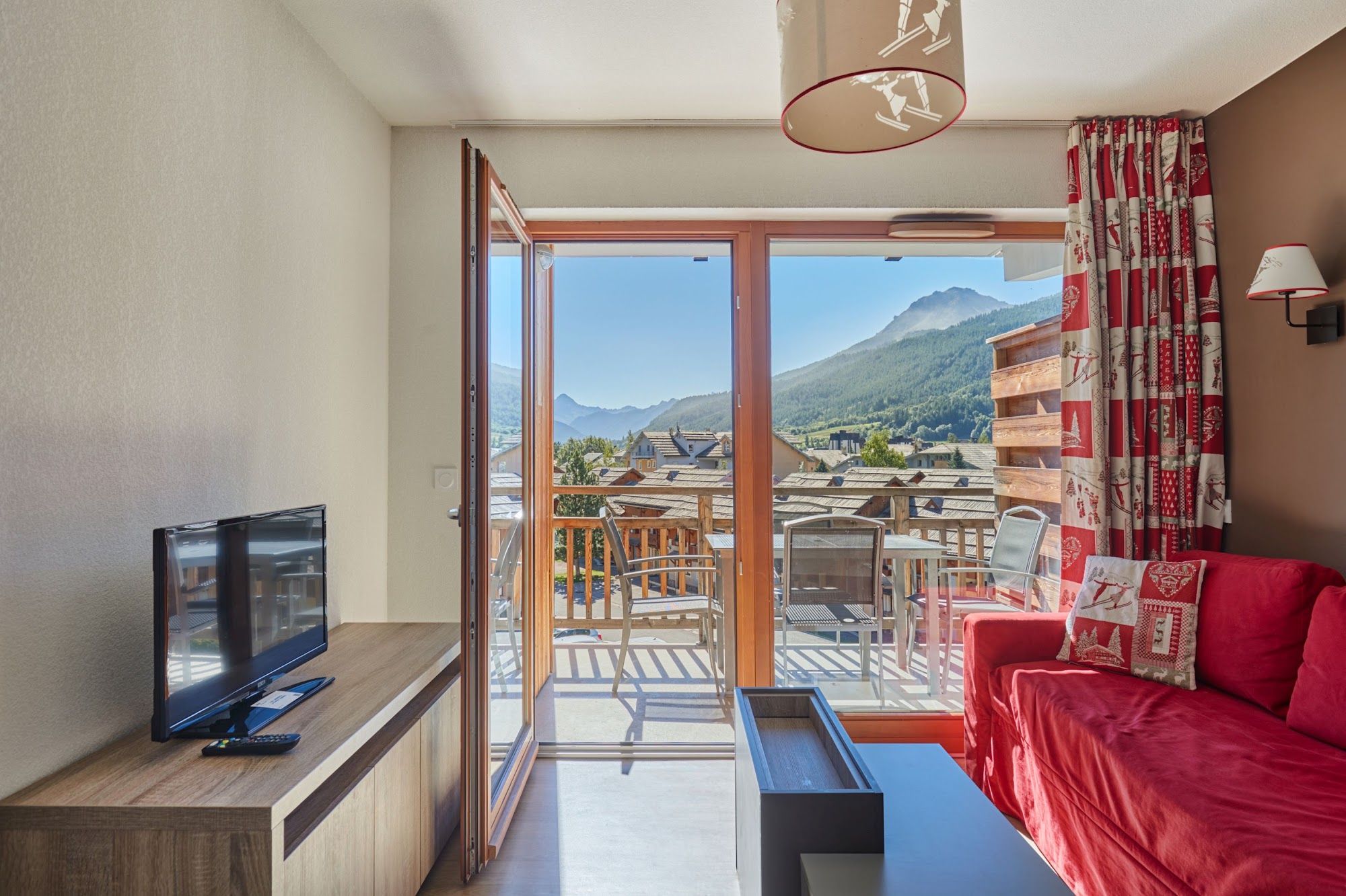 image Living area with a red sofa and glass doors to the balcony