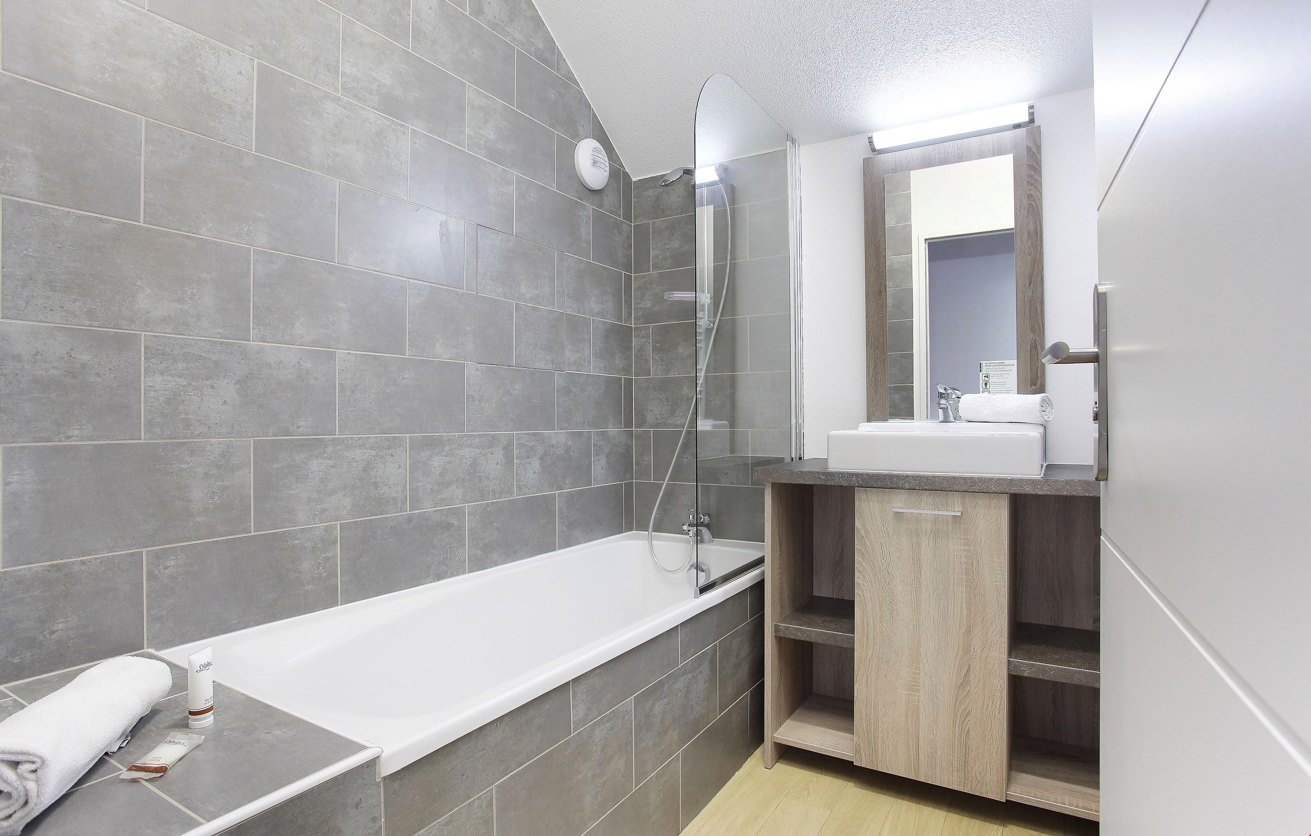 image A full bathroom including a vanity and a shower-tub combination completes this apartment