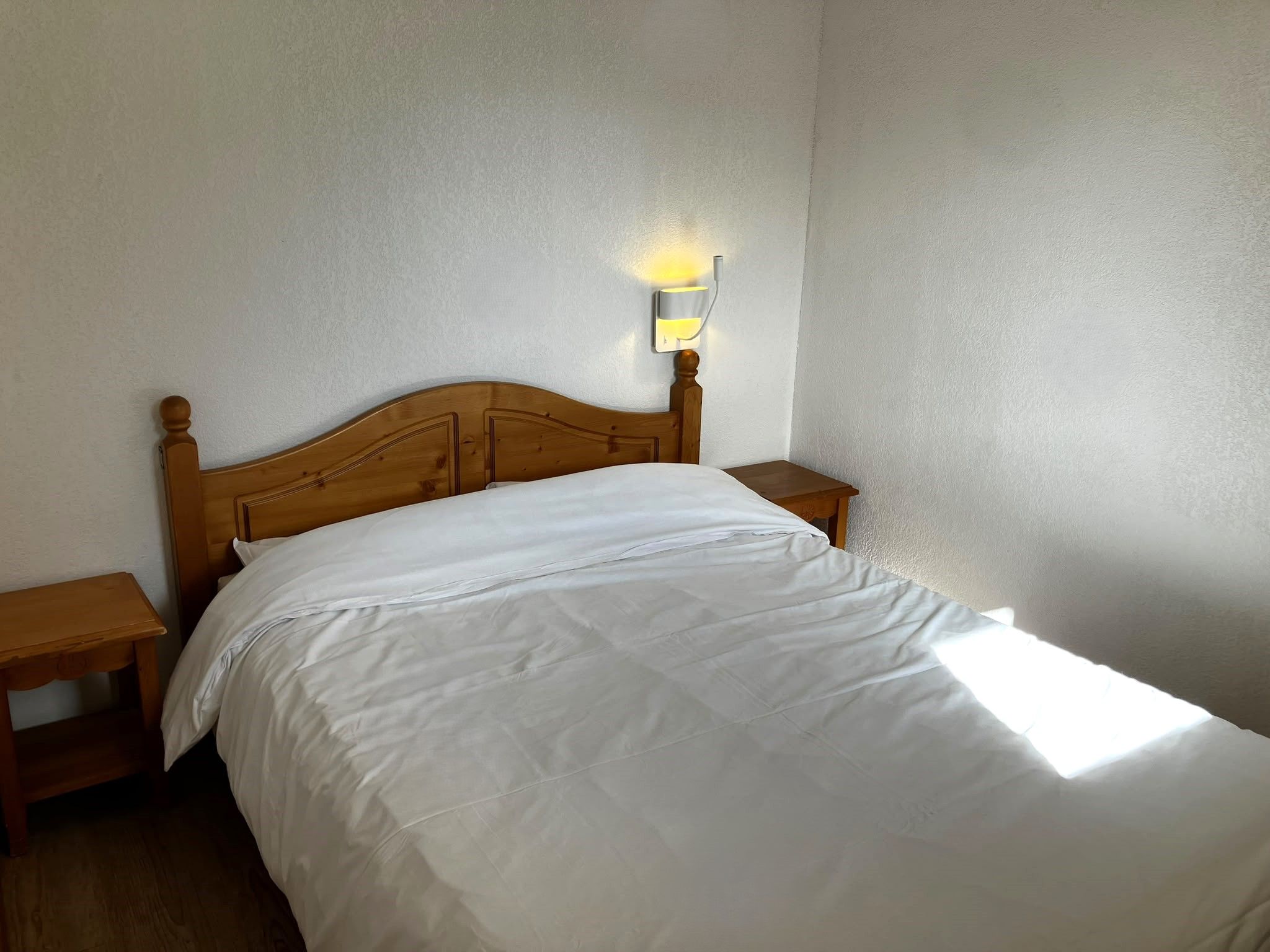 image Retreat to the bedroom, furnished with a wooden bed frame and warm bedside lighting