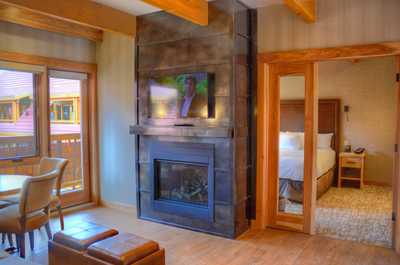 The bright, open-concept living space features a flat panel TV and a majestic gas fireplace.