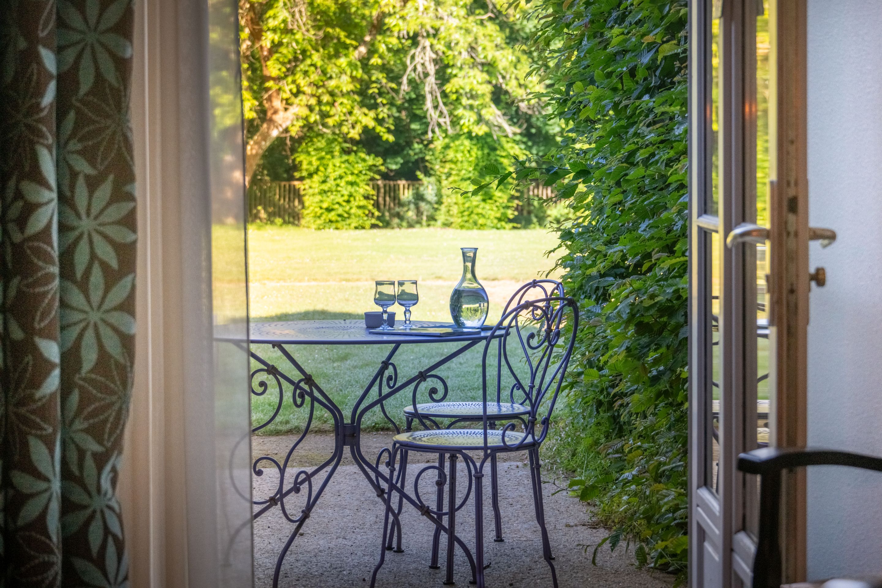 image A round metal table for two sits on the patio, tucked among the greenery outside.
