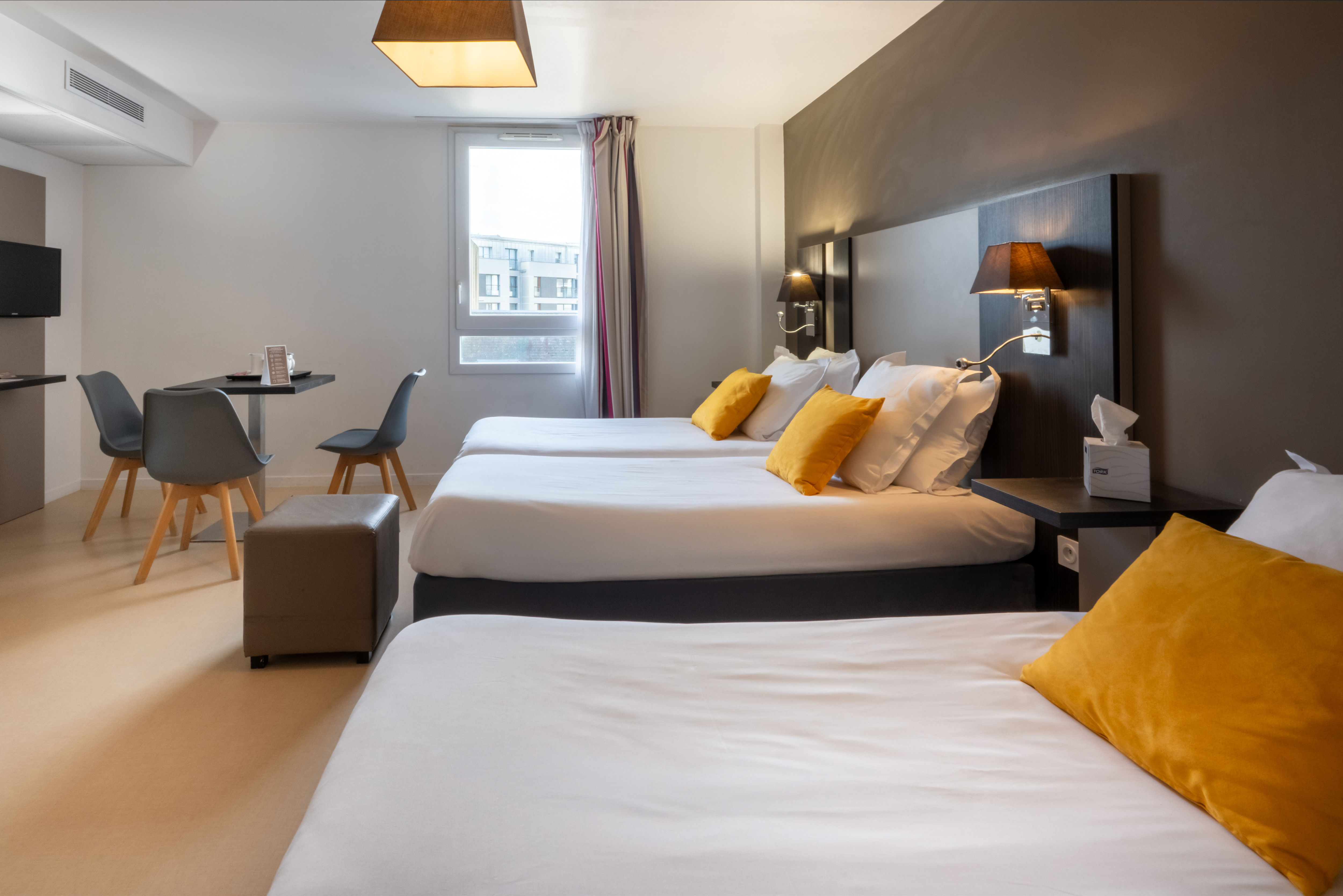 image The spacious Superior Studio showcases a modern aesthetic with two cozy beds adorned with vibrant yellow cushions, perfect for accommodating up to three guests.