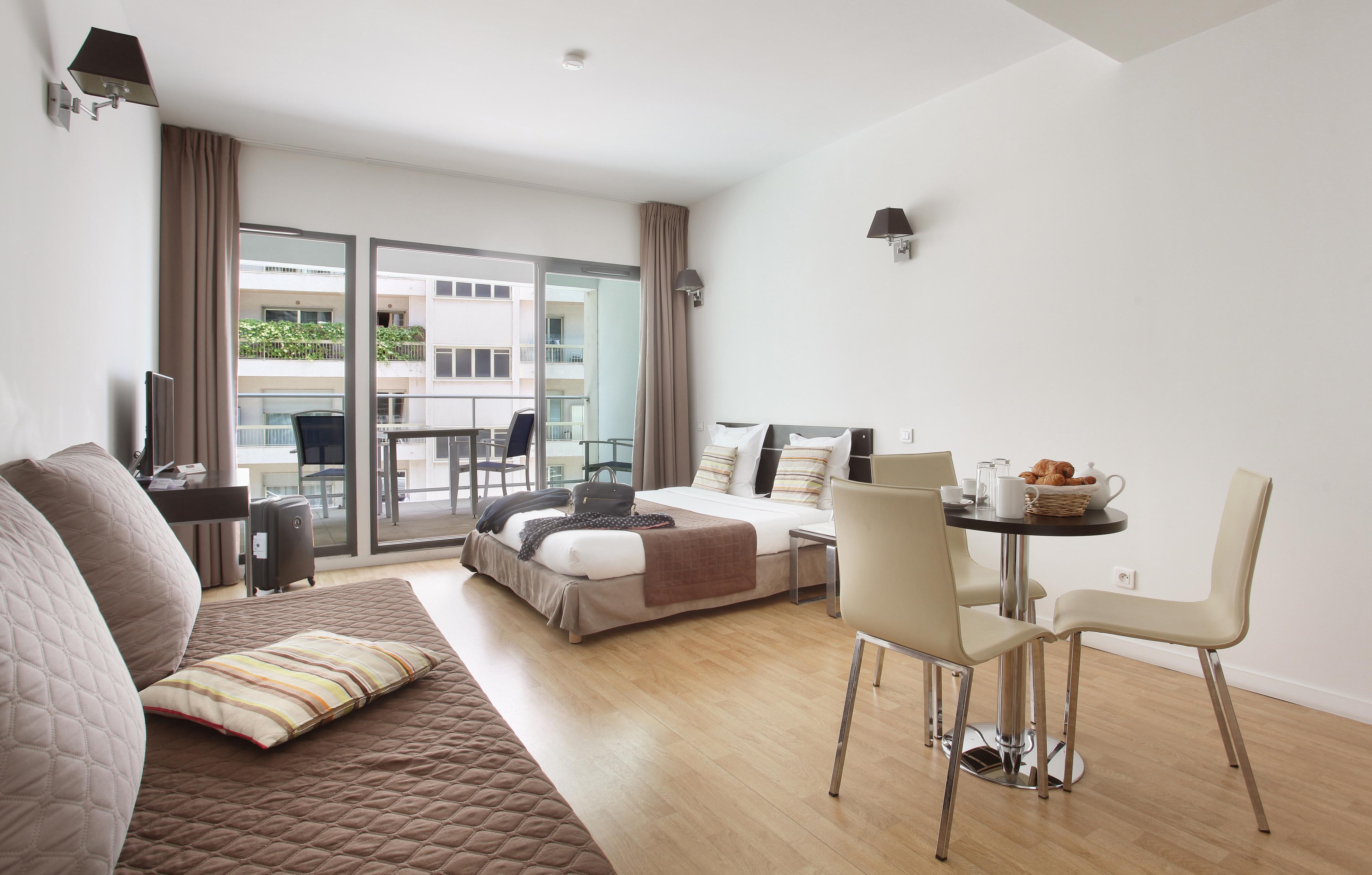 image Step into a sunny studio with seating and dining space, opening onto a private balcony for fresh-air moments.