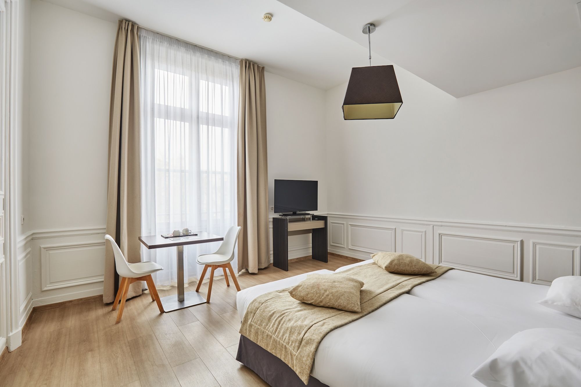 image Refined double room with classic wall paneling, large windows, and an inviting, restful atmosphere.