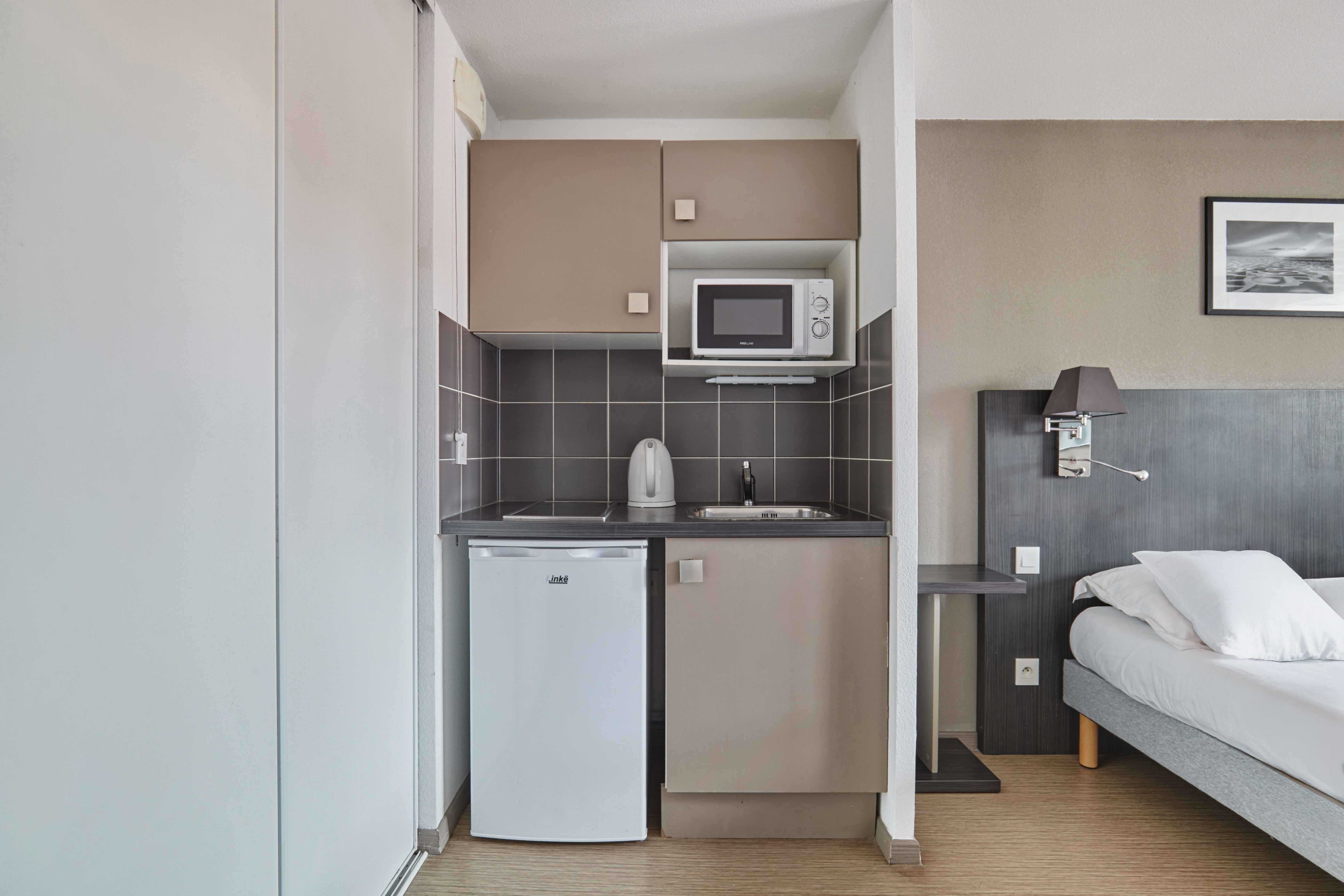 image Compact kitchenette equipped with a microwave and fridge for convenient in-room dining.