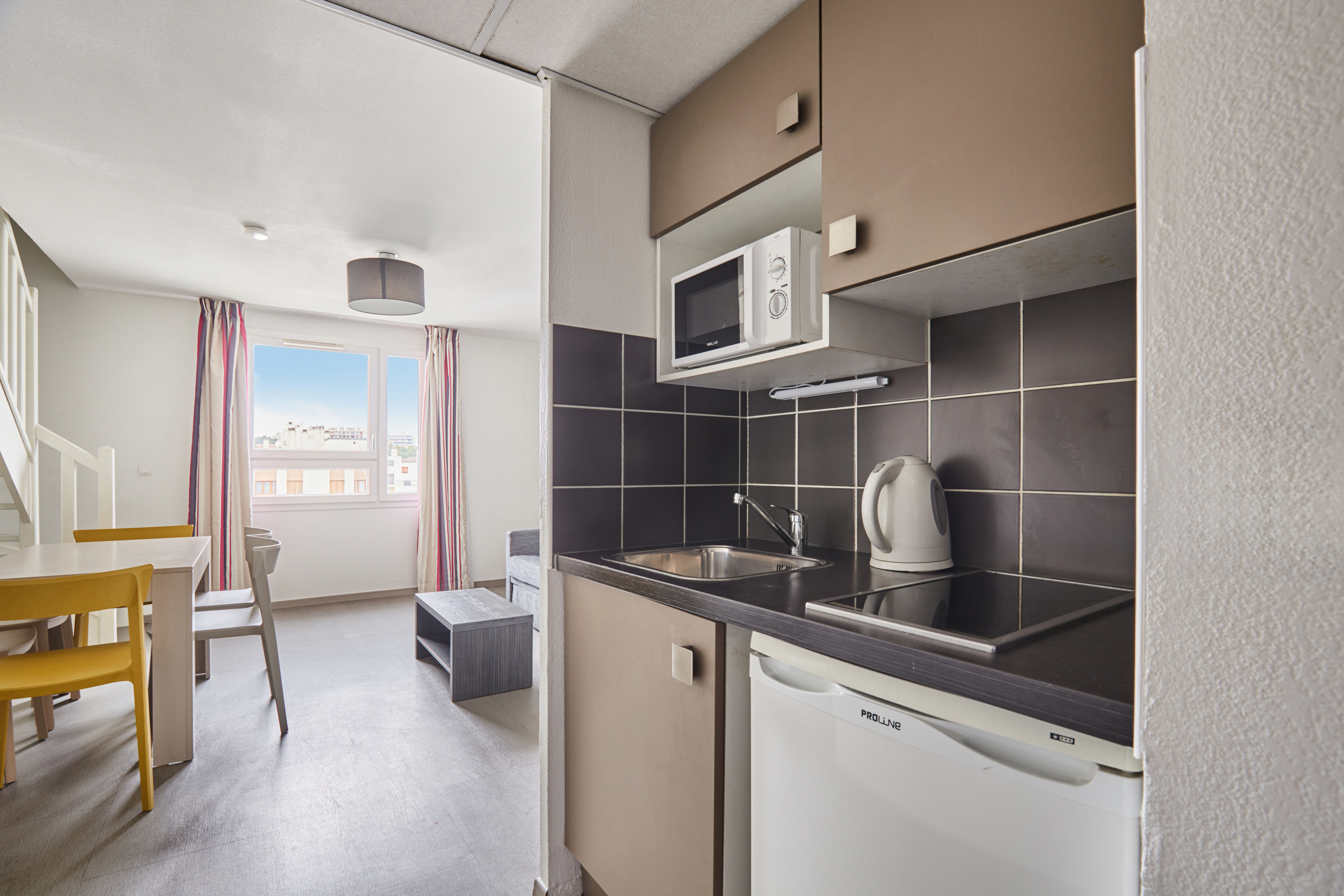 image Functional kitchenette with modern appliances and clean design ideal for easy in-room cooking.