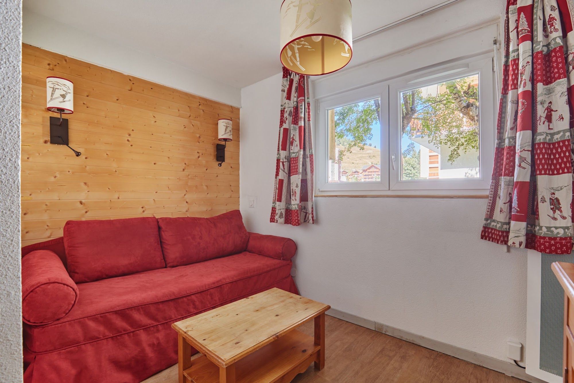 image Red sofa bed with a wooden coffee table and wall lamps