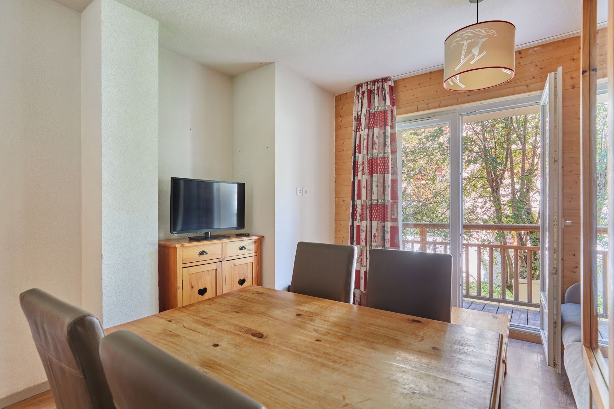 image TV on a wooden cabinet near the dining area and balcony