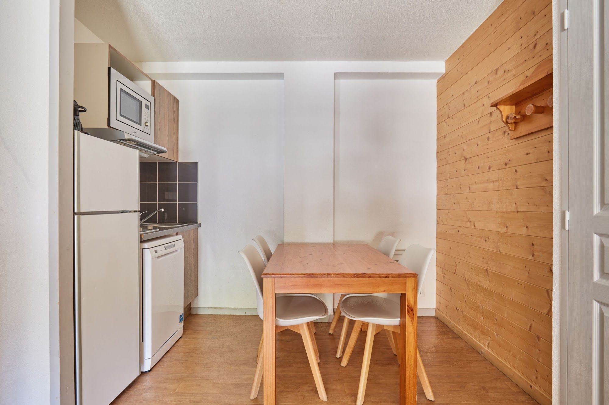 image Dining table with white chairs beside the kitchenette