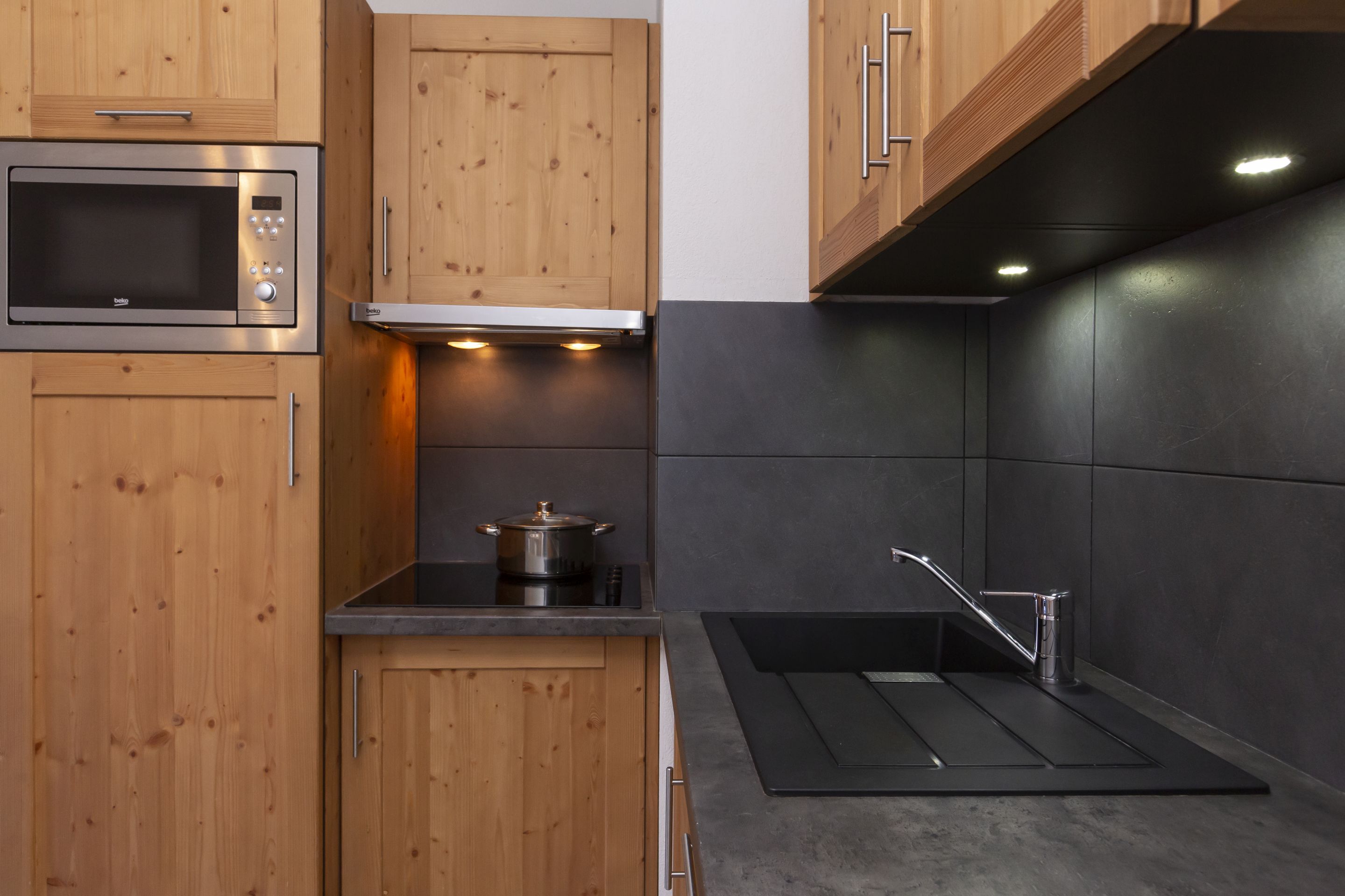 image The kitchenette's dark countertops and wooden cabinetry keep the mountain aesthetic consistent throughout the apartment.