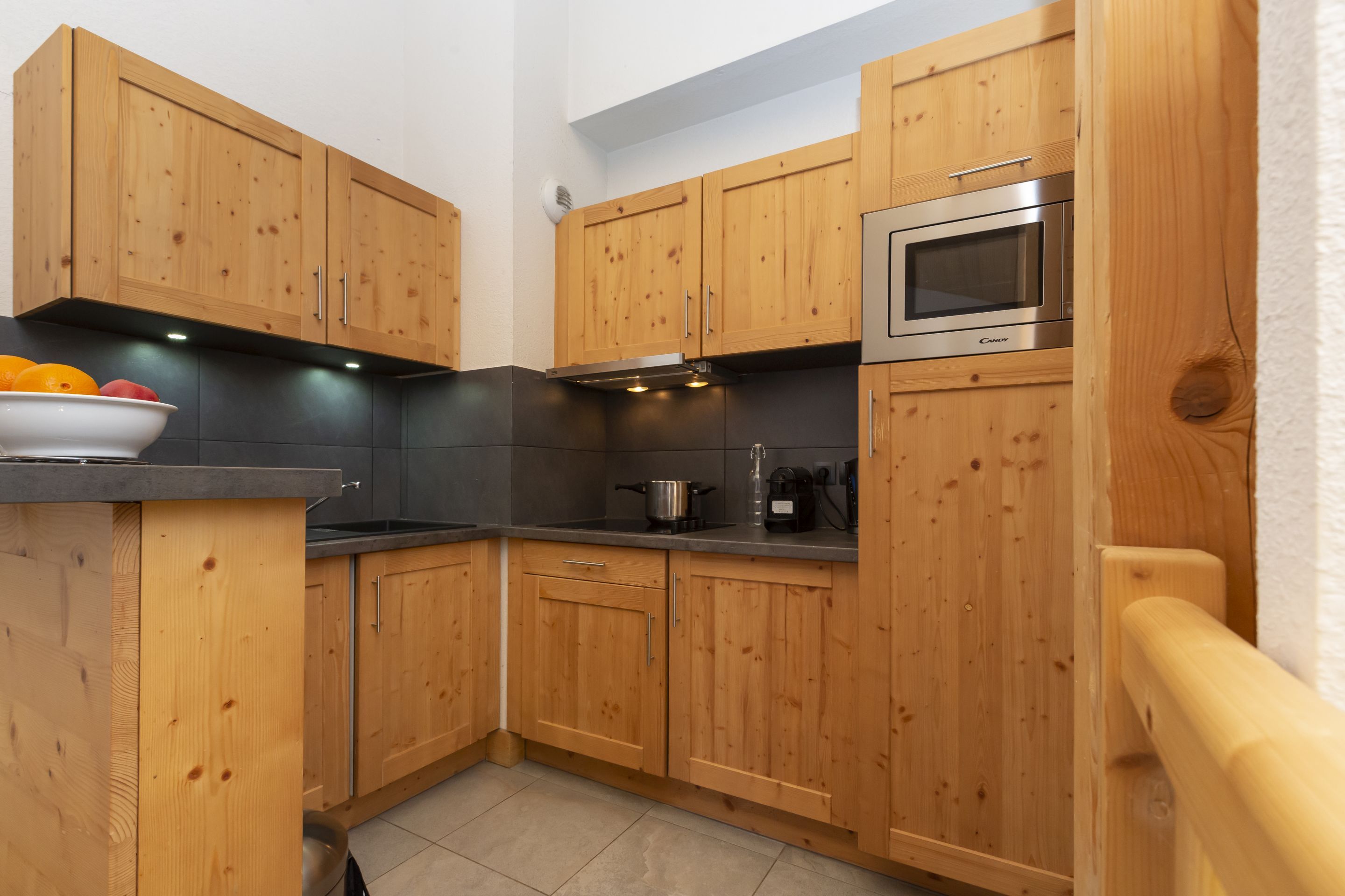 image The kitchenette's wooden cabinetry and dark countertops keep everything within reach for group breakfasts before the gondola.