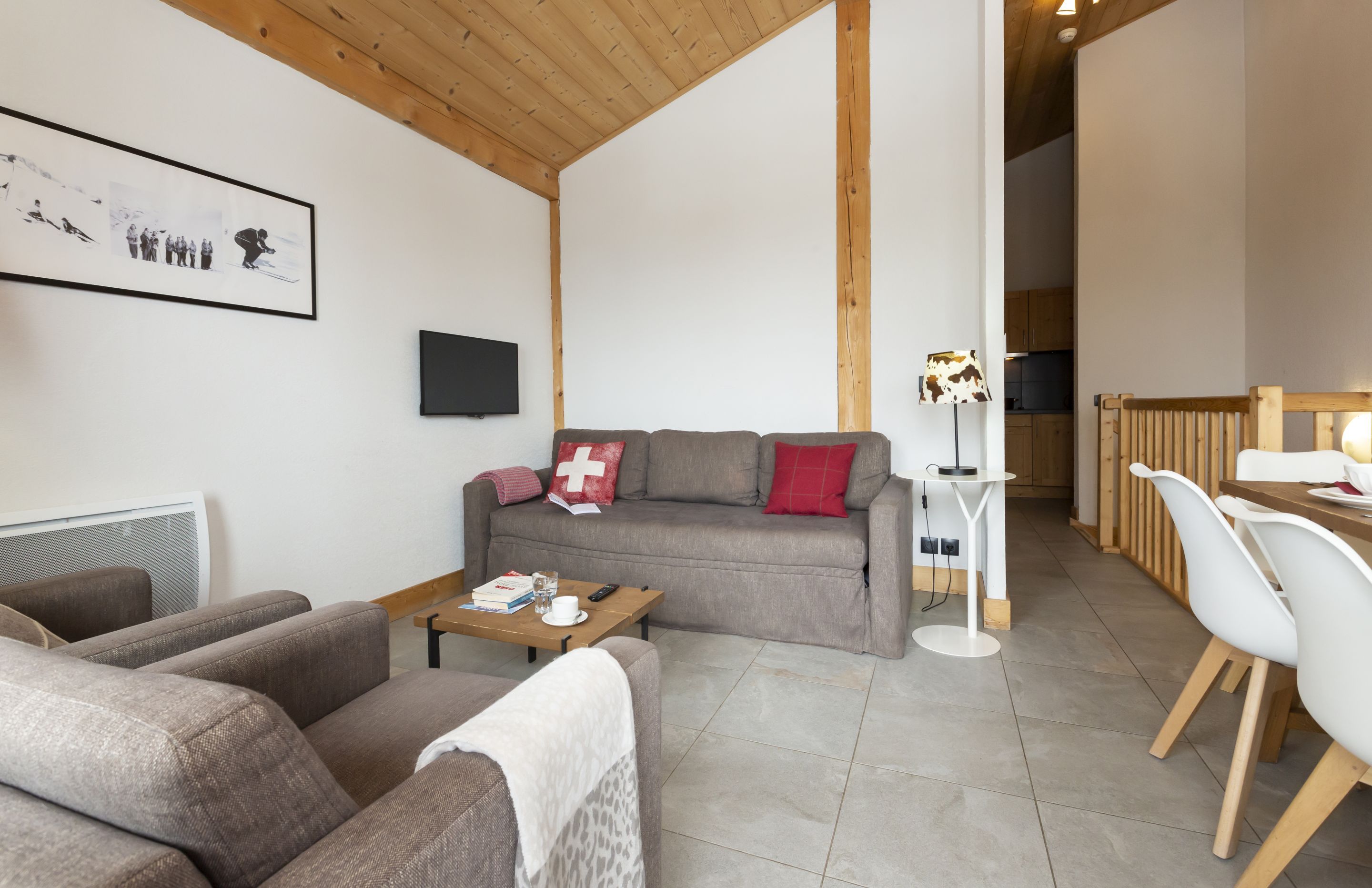 image The living room's sloped wooden ceiling, mounted TV, and large windows bring the Alpine atmosphere inside.