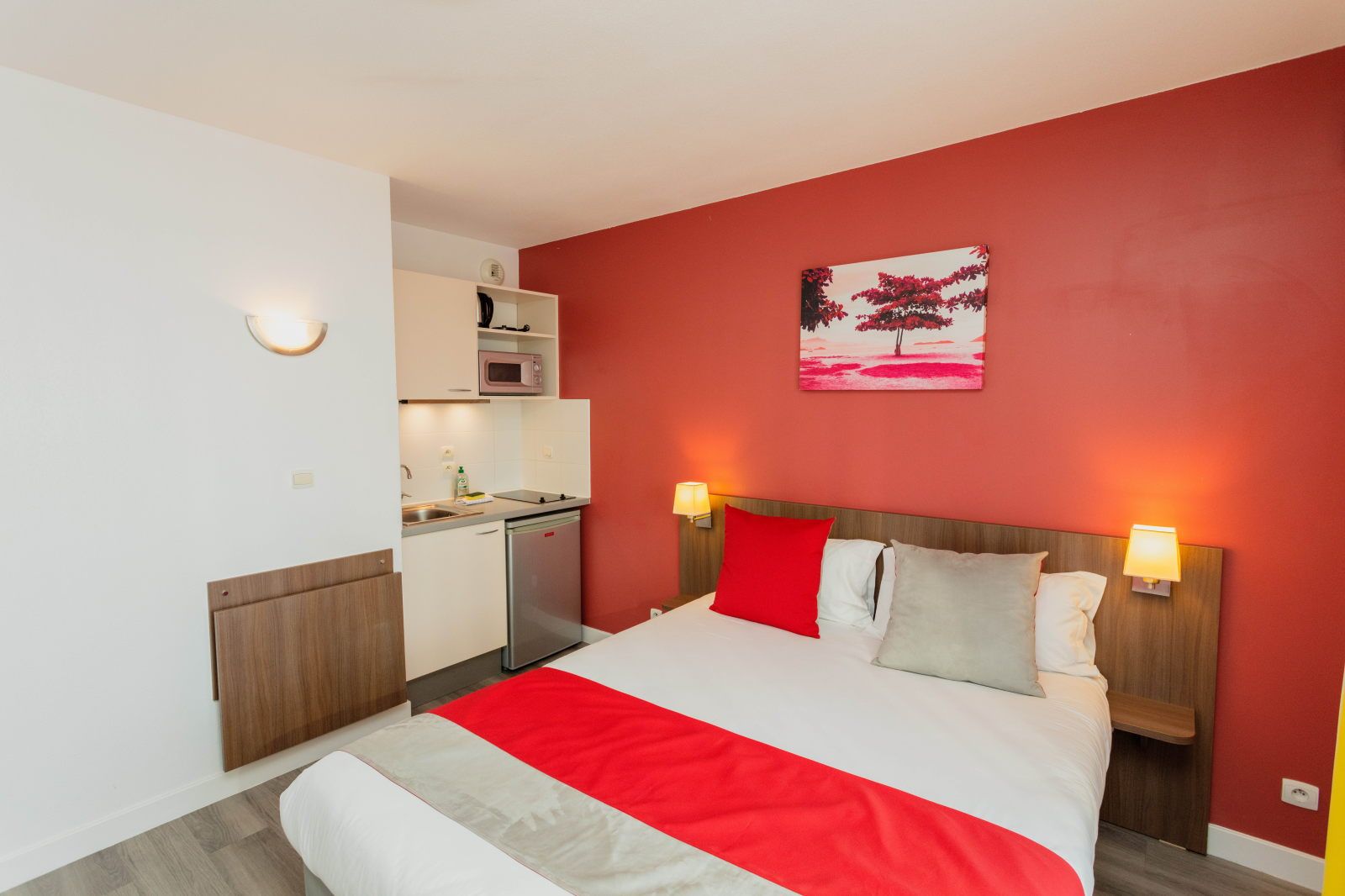 image Studio room with a plush bed, two bedside lamps, and a kitchenette along the side wall