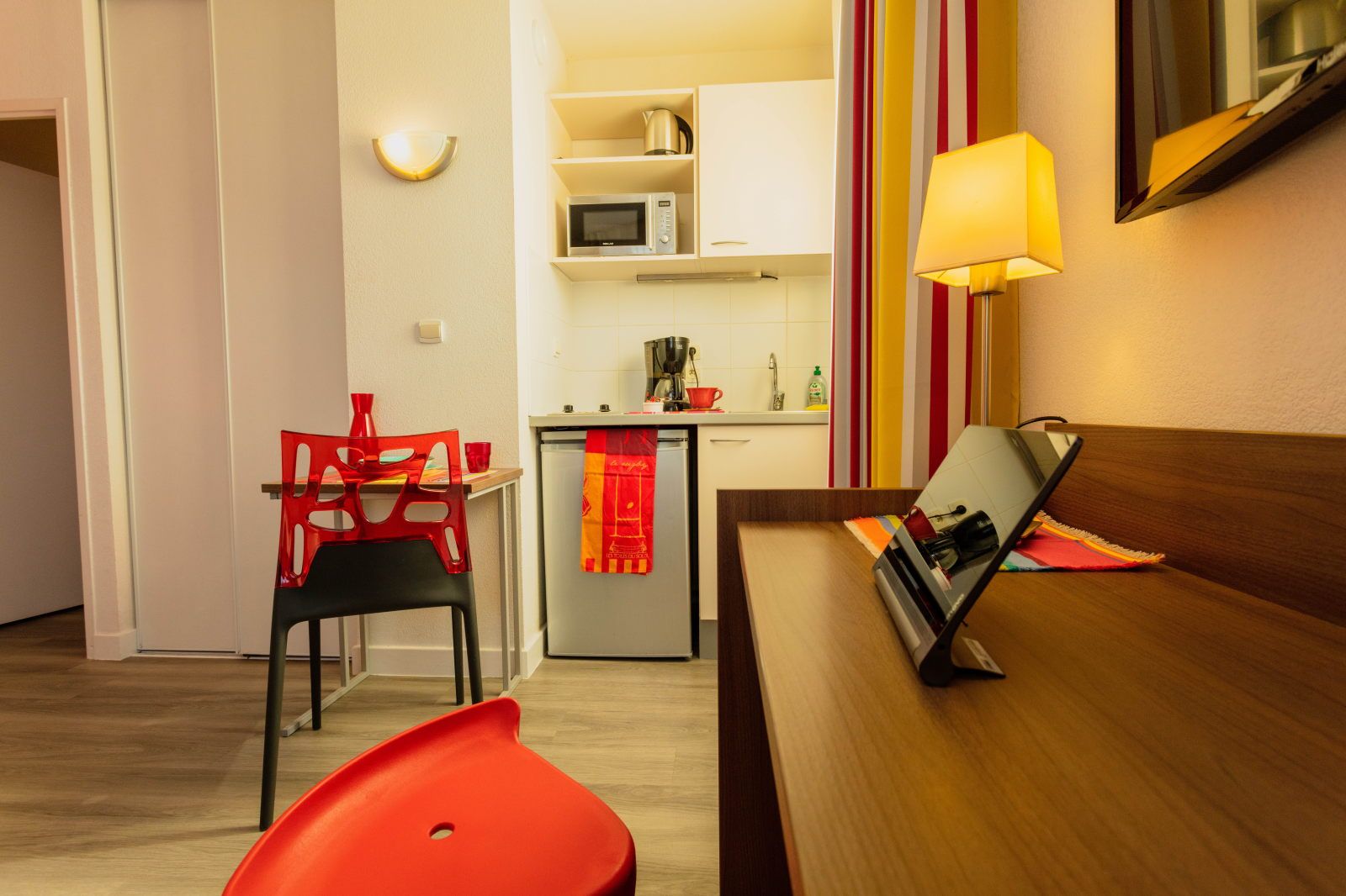 image Dining setup features a red chair, small table, and kitchen appliances in a functional area