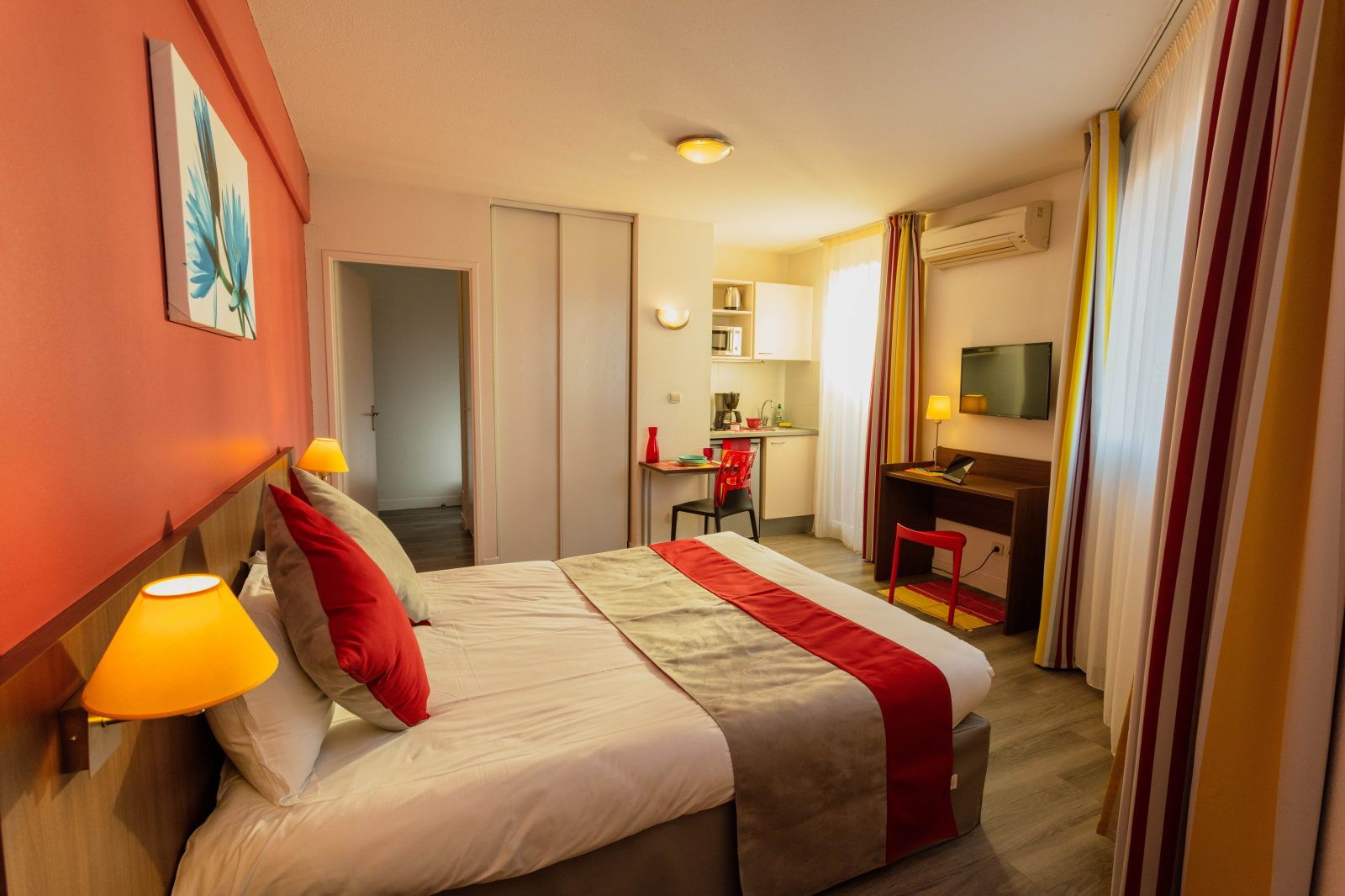 image Room layout shows a kitchenette area, work desk, and TV across from the bed