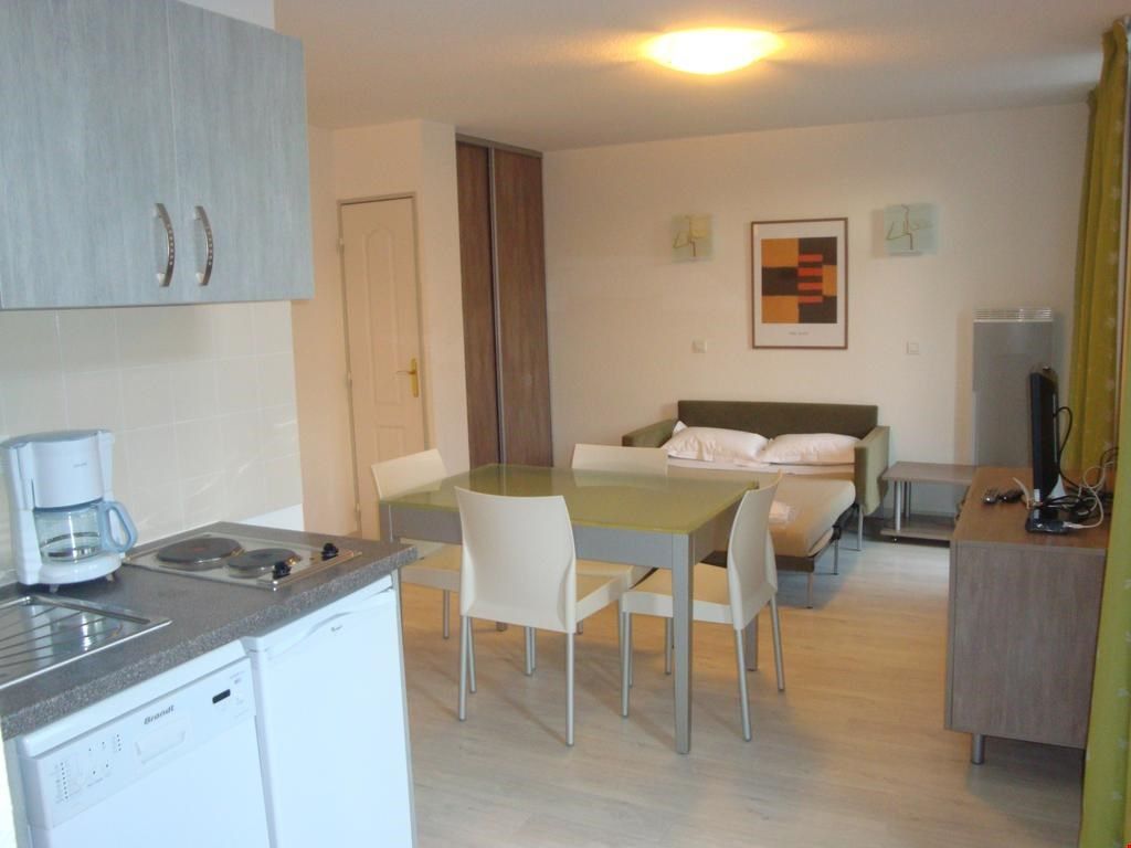 image Living area with a sofa bed, dining table, and kitchenette.
