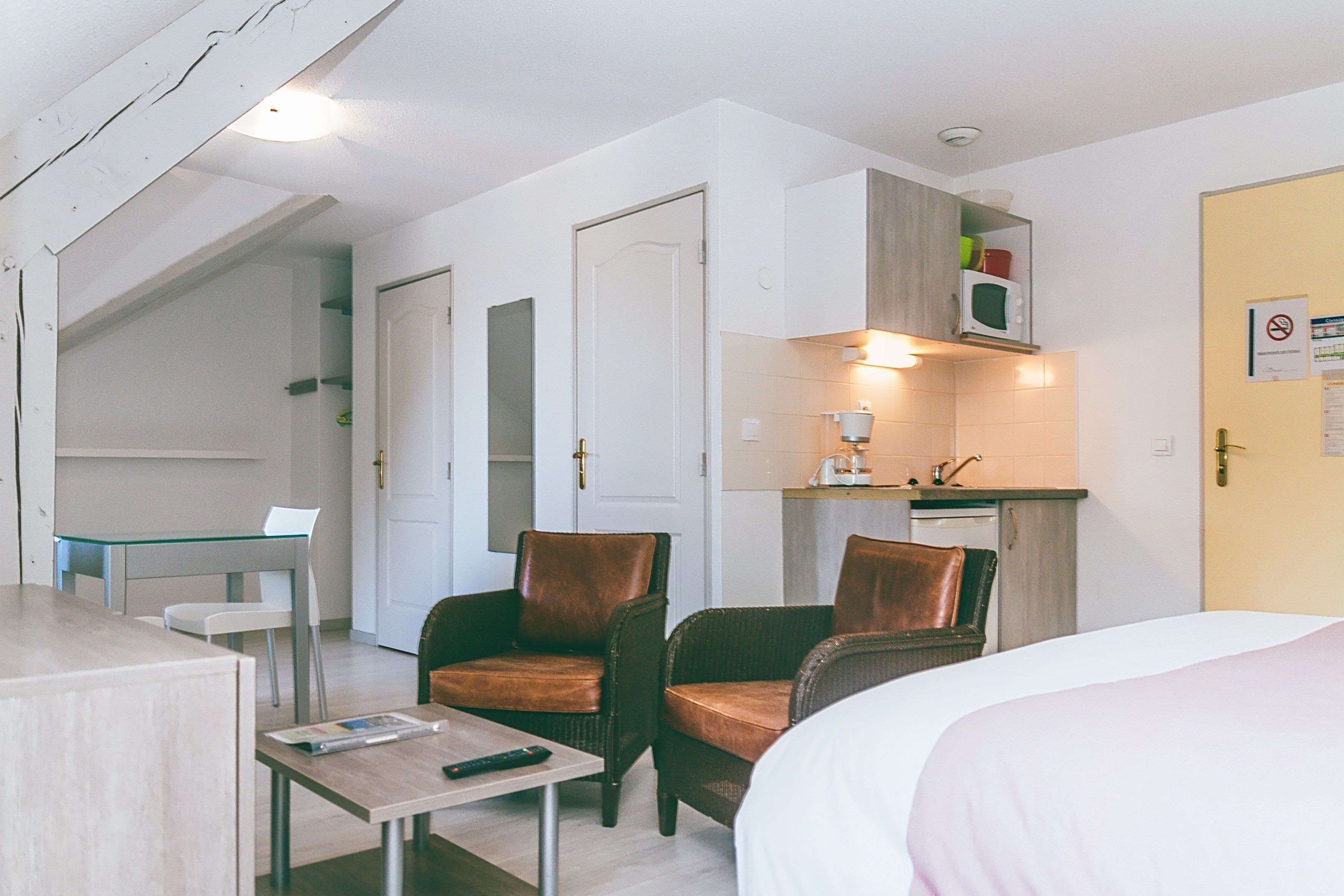 image Living area with two armchairs and a kitchenette.