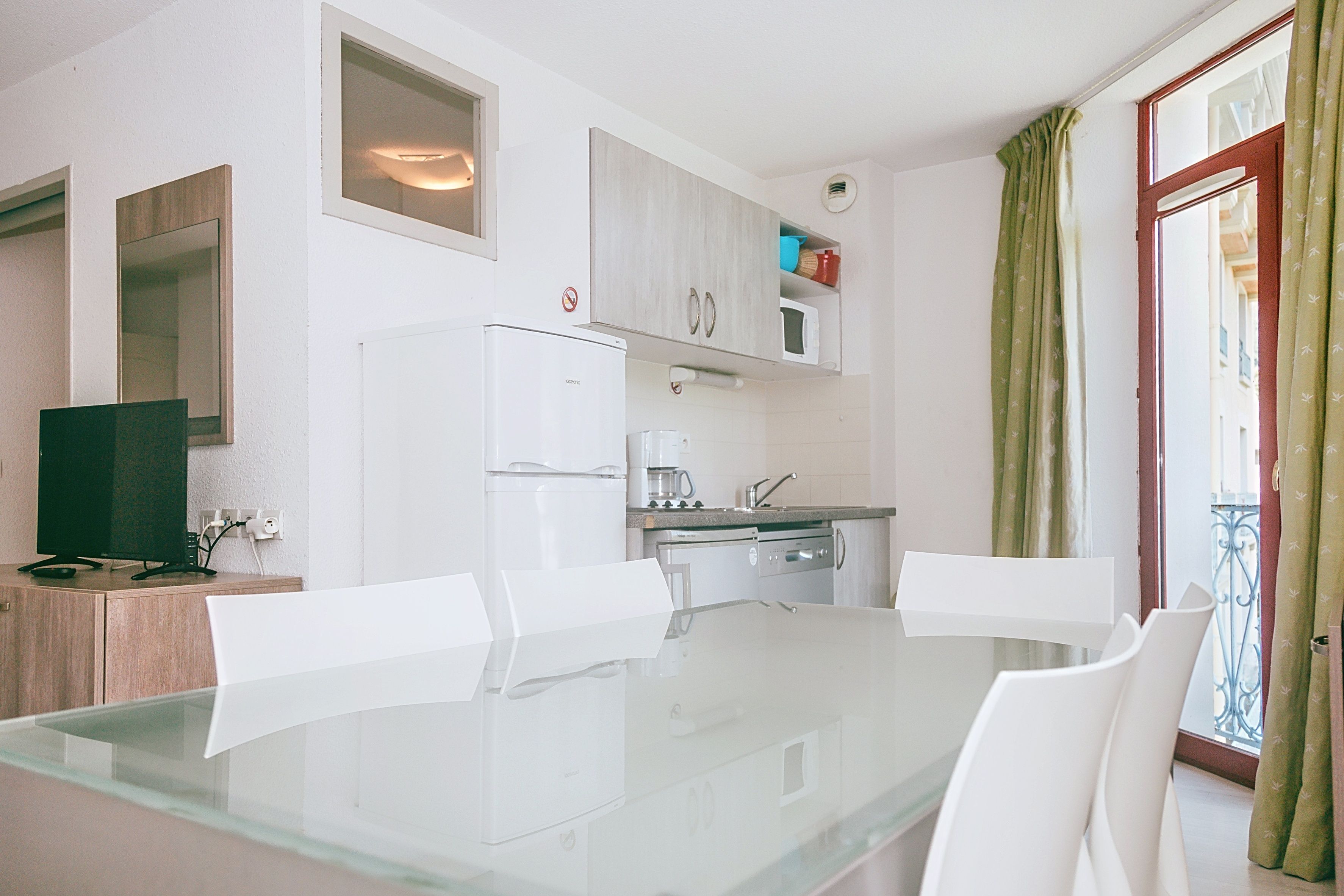 image Kitchen area with appliances and a glass dining table.