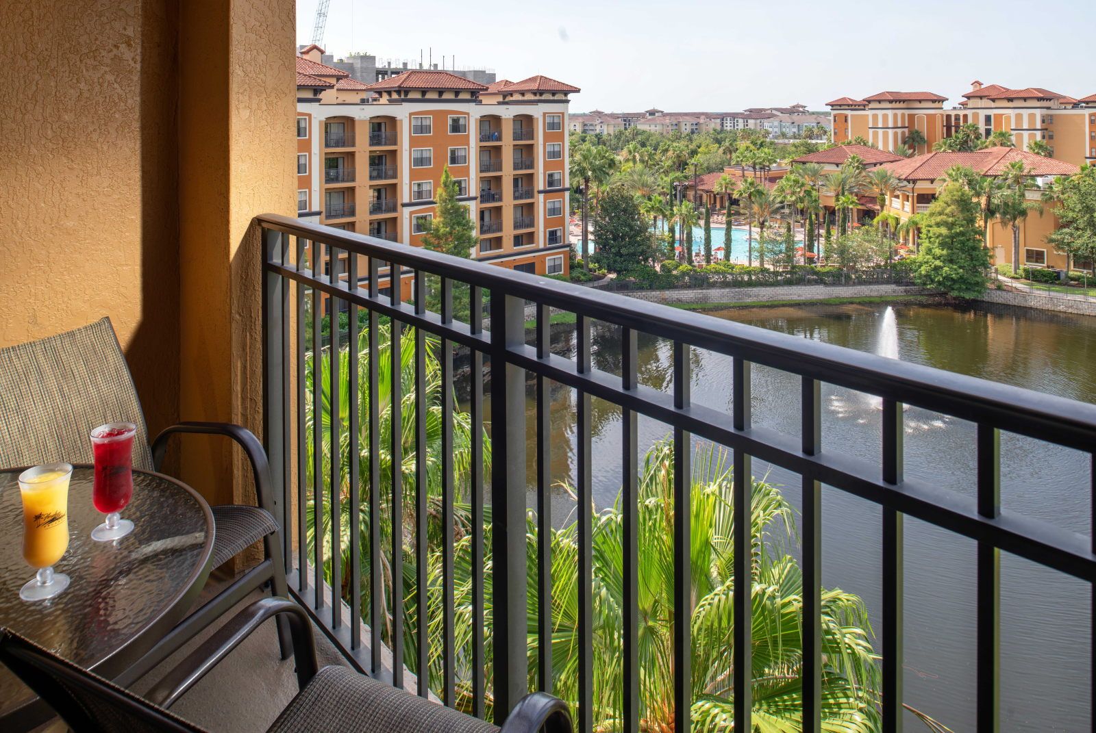 image Step out to the furnished balcony overlooking the lake fountain, pool, and terracotta-roofed buildings beyond