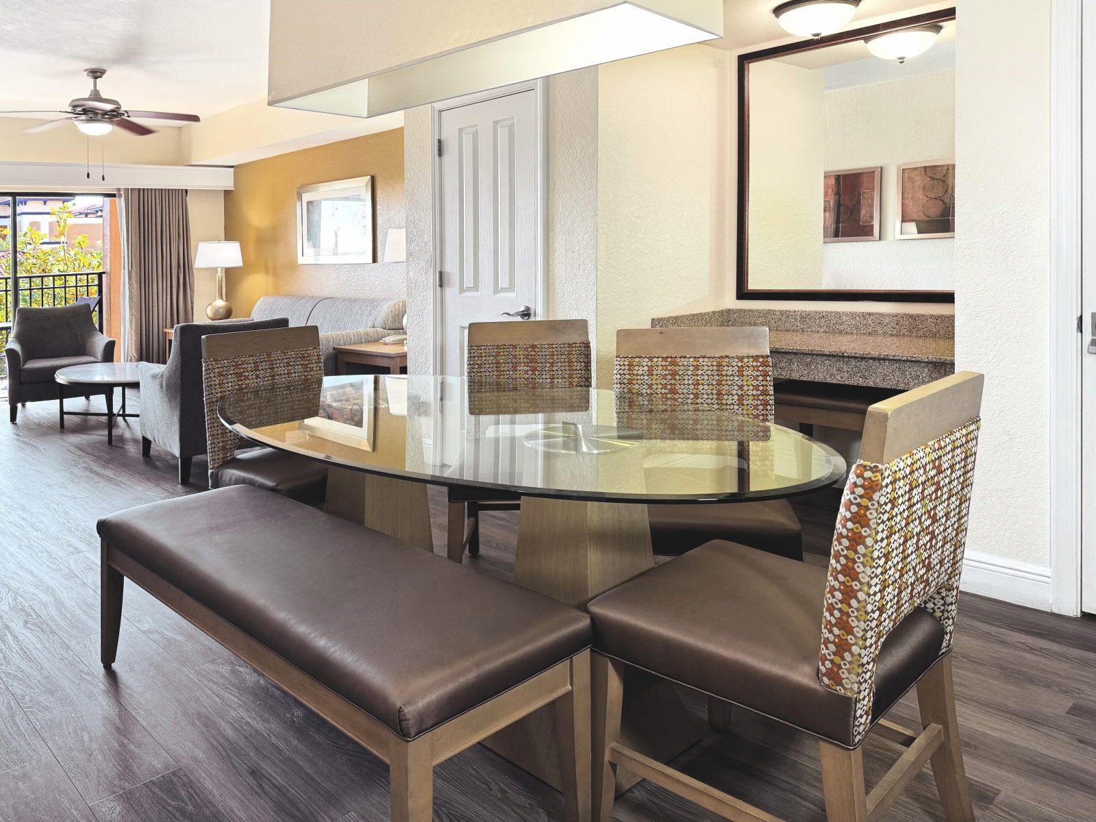 image Round glass dining table with six chairs, sofa and large window visible in the open-plan background