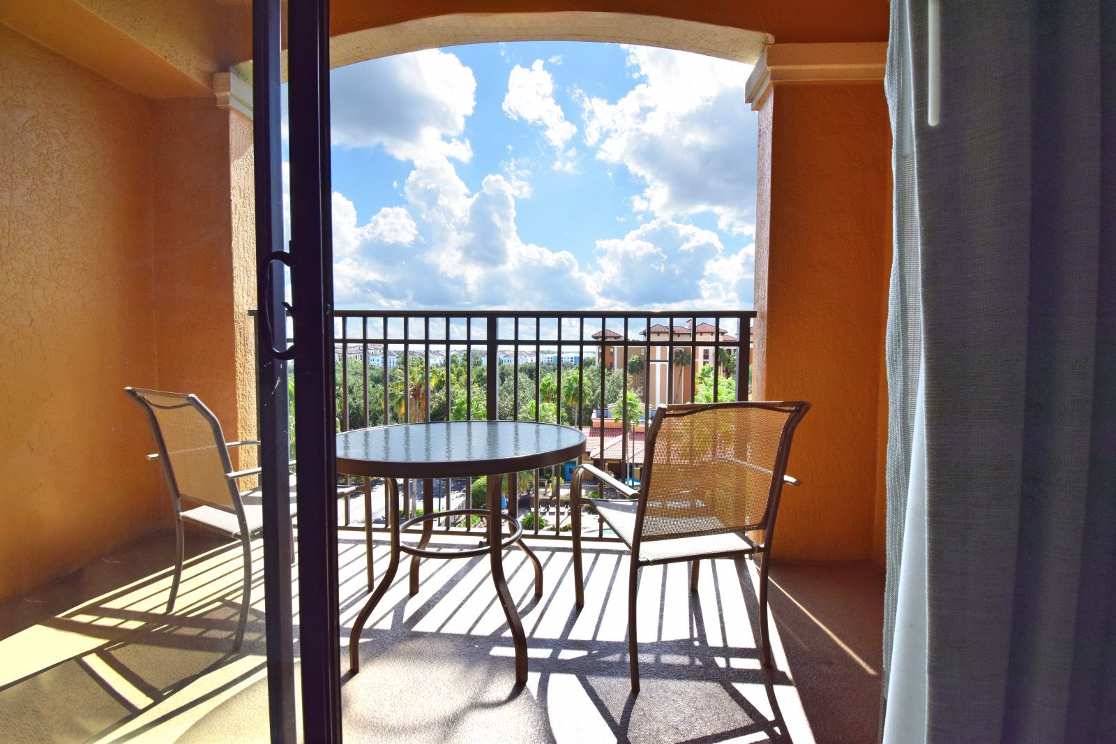 image Round table and two chairs on the private balcony, overlooking green trees under a clear sky
