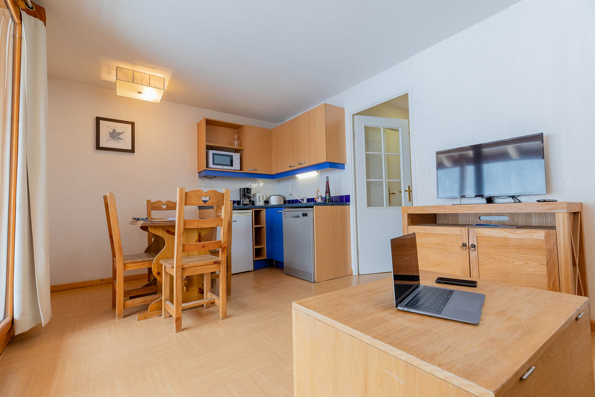 image Kitchen area with dining table, refrigerator and microwave