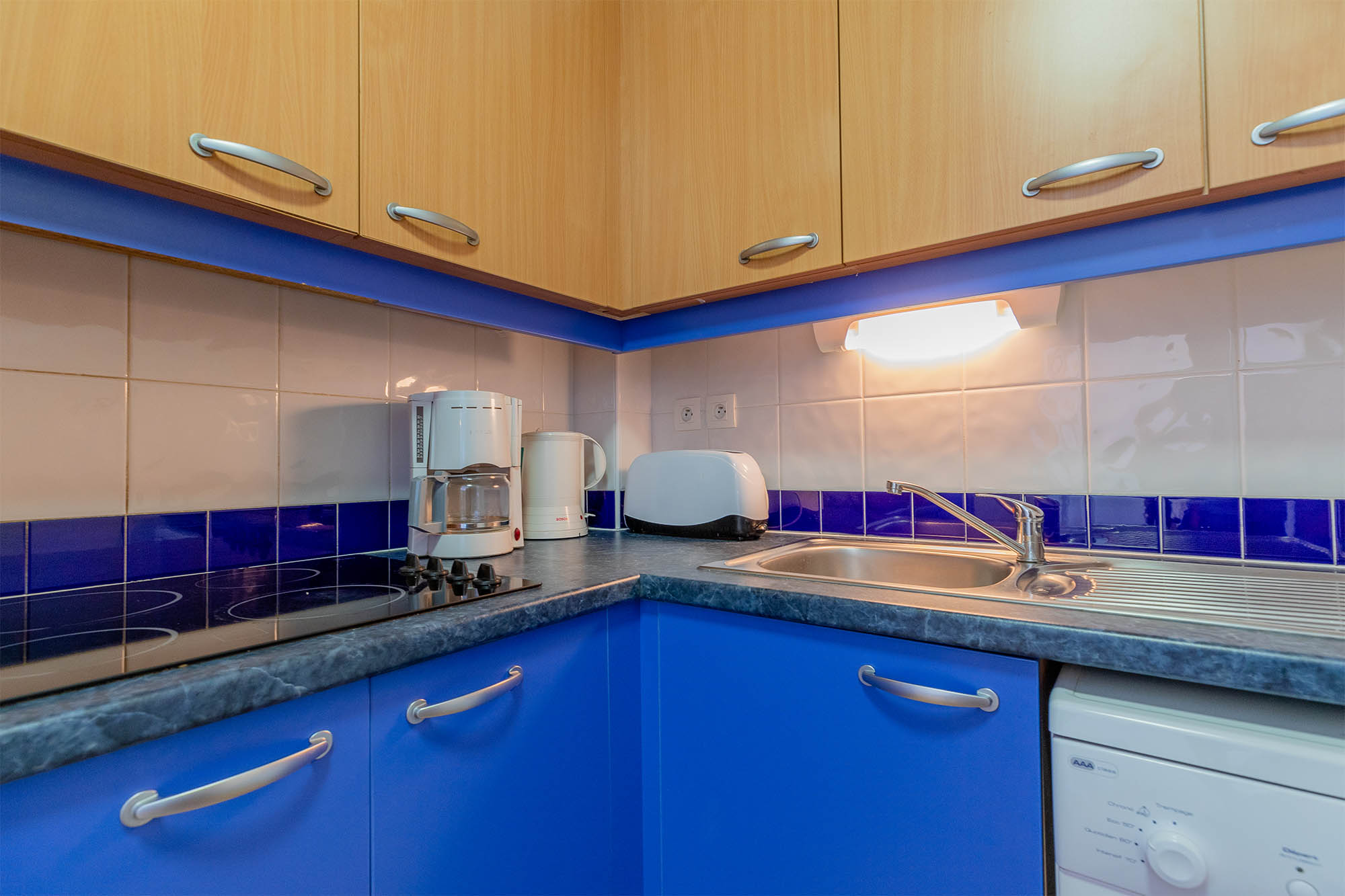 image Kitchen with blue cabinets, stovetop, toaster and coffee maker