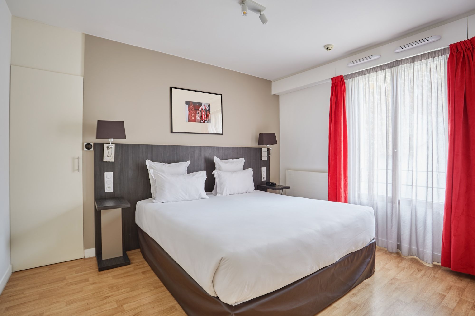 image Warm-toned bedroom with red accents and large windows, offering a cozy space to unwind.
