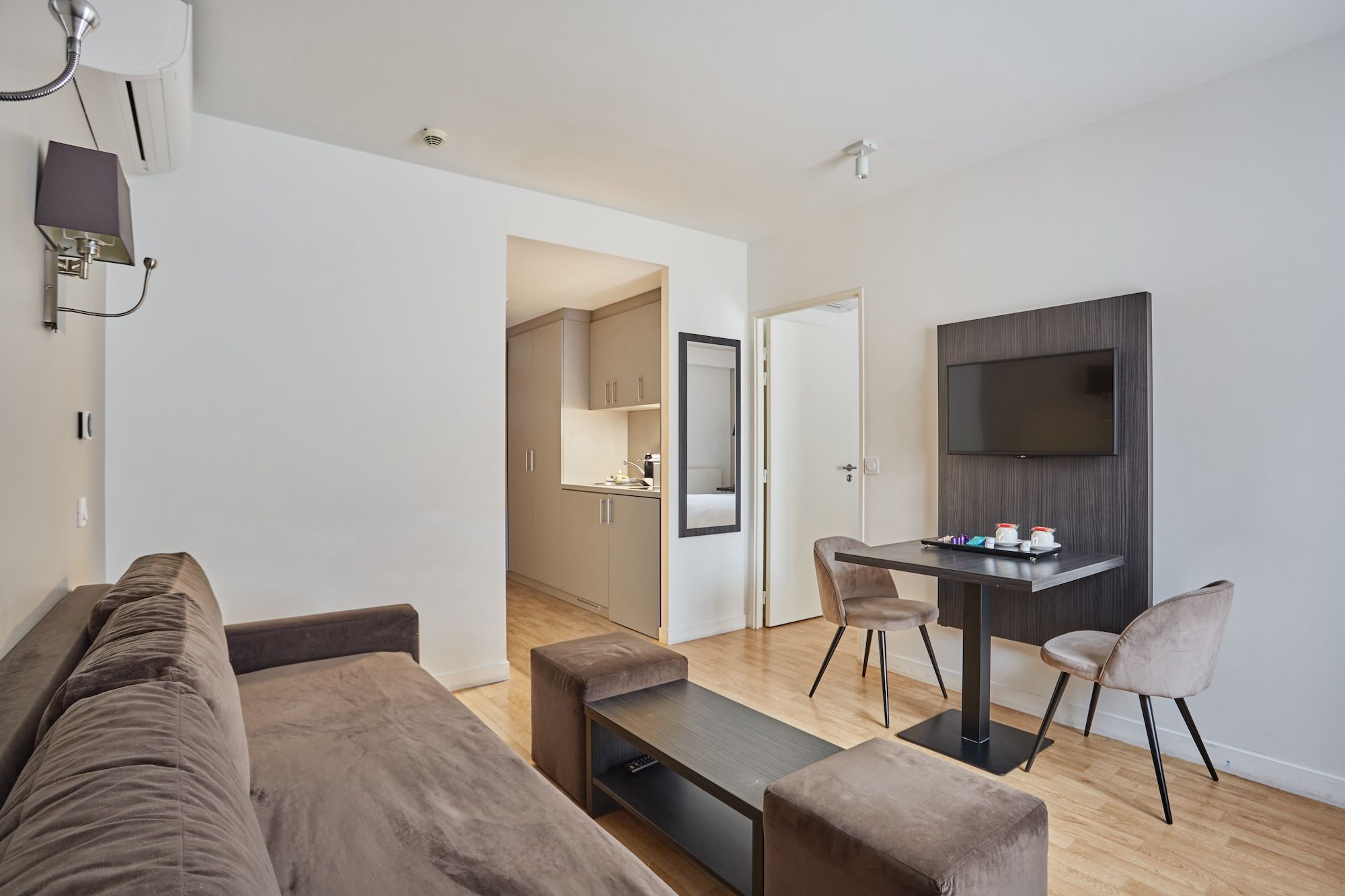 image Expanding into the main living area, you'll discover a comfortable sofa set, a dining space for two, and a mounted TV, creating an ideal setup for relaxation and entertainment in your Paris retreat.
