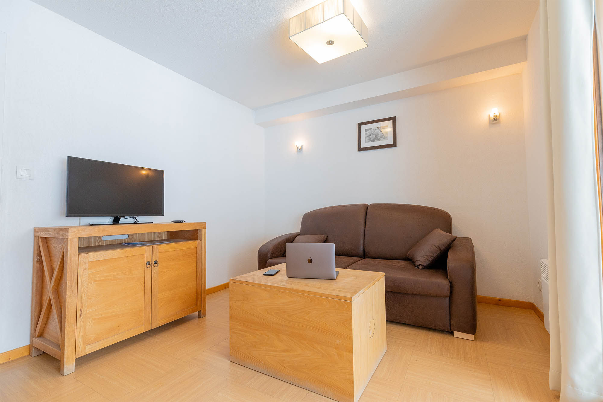 image Living area with sofa bed, wooden table and TV
