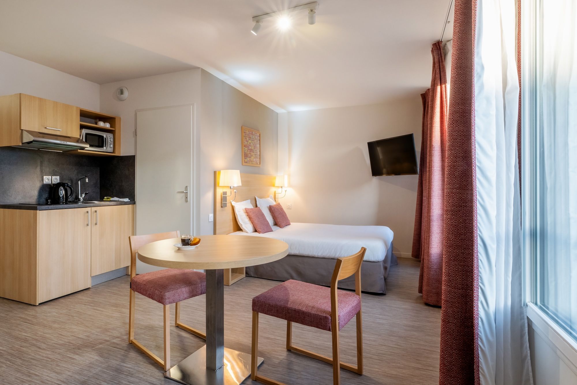 image A cozy studio apartment featuring modern furnishings, a compact kitchenette, and warm lighting.