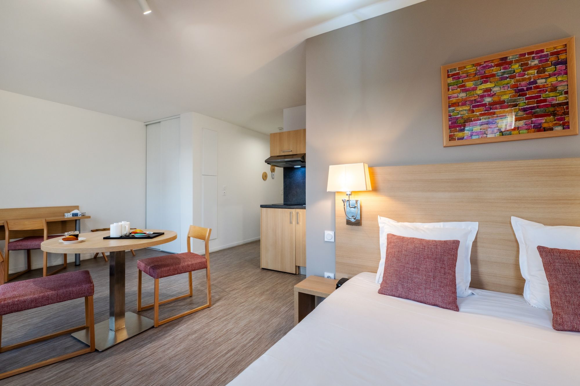 image An inviting living area showcasing a well-appointed kitchenette and a comfortable double bed with decorative pillows.